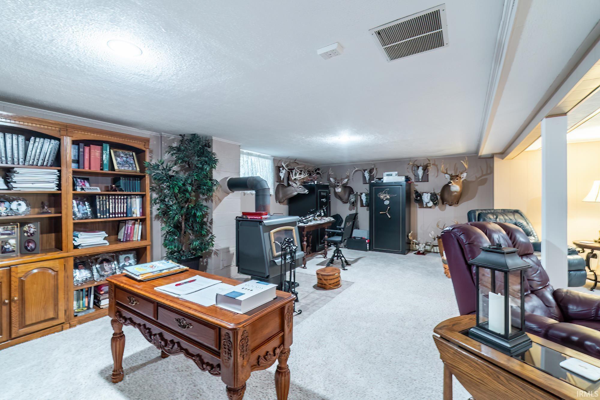 Finished lower level featuring recessed lighting, a wood-burning stove, built-in shelving, carpet flooring, and exposed ceiling beams