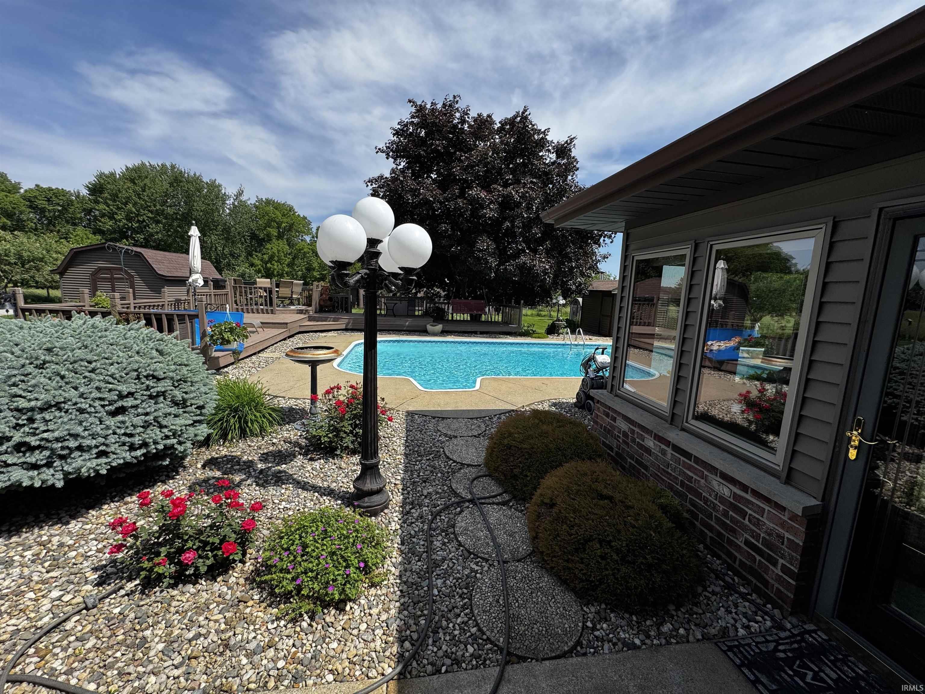 Exterior featuring an in-ground swimming pool, multi-level wood deck, and a detached shed