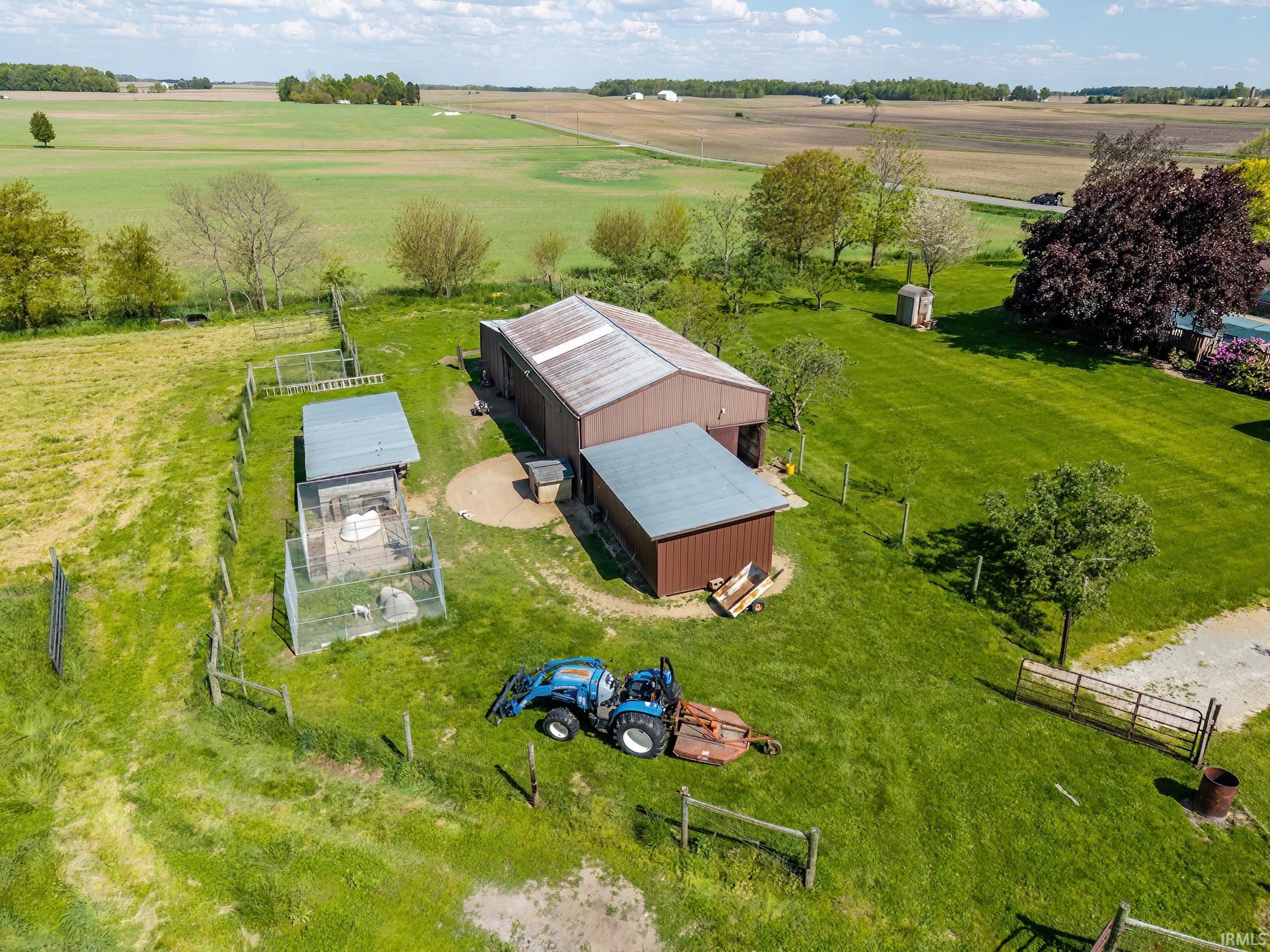 Expansive rural property featuring a large brown barn with a metal roof, an additional detached outbuilding, and fenced enclosures