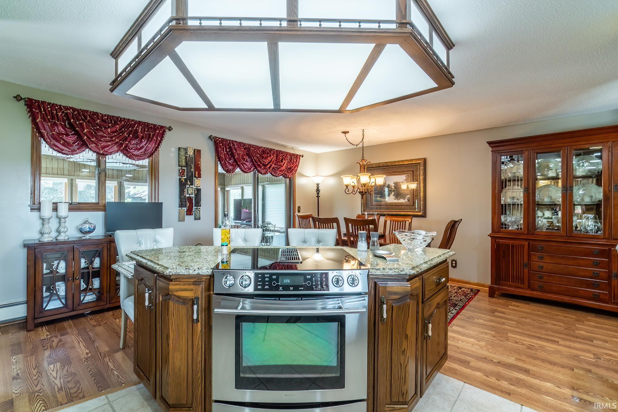 Central kitchen island with a granite countertop, stainless steel cooktop, and oven