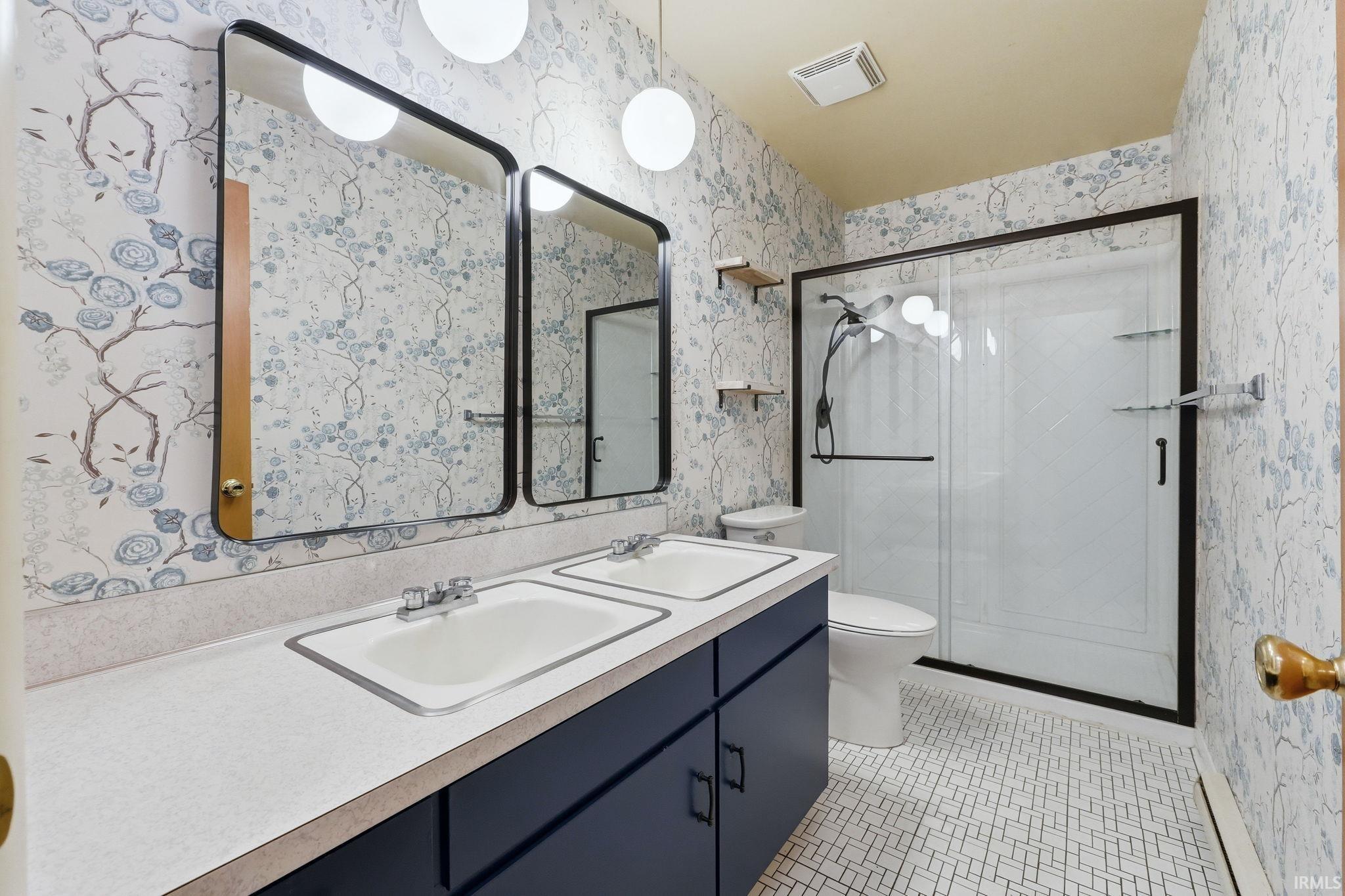 Bathroom featuring a dual vanity with rectangular sinks, a white countertop, and a dark blue base cabinet