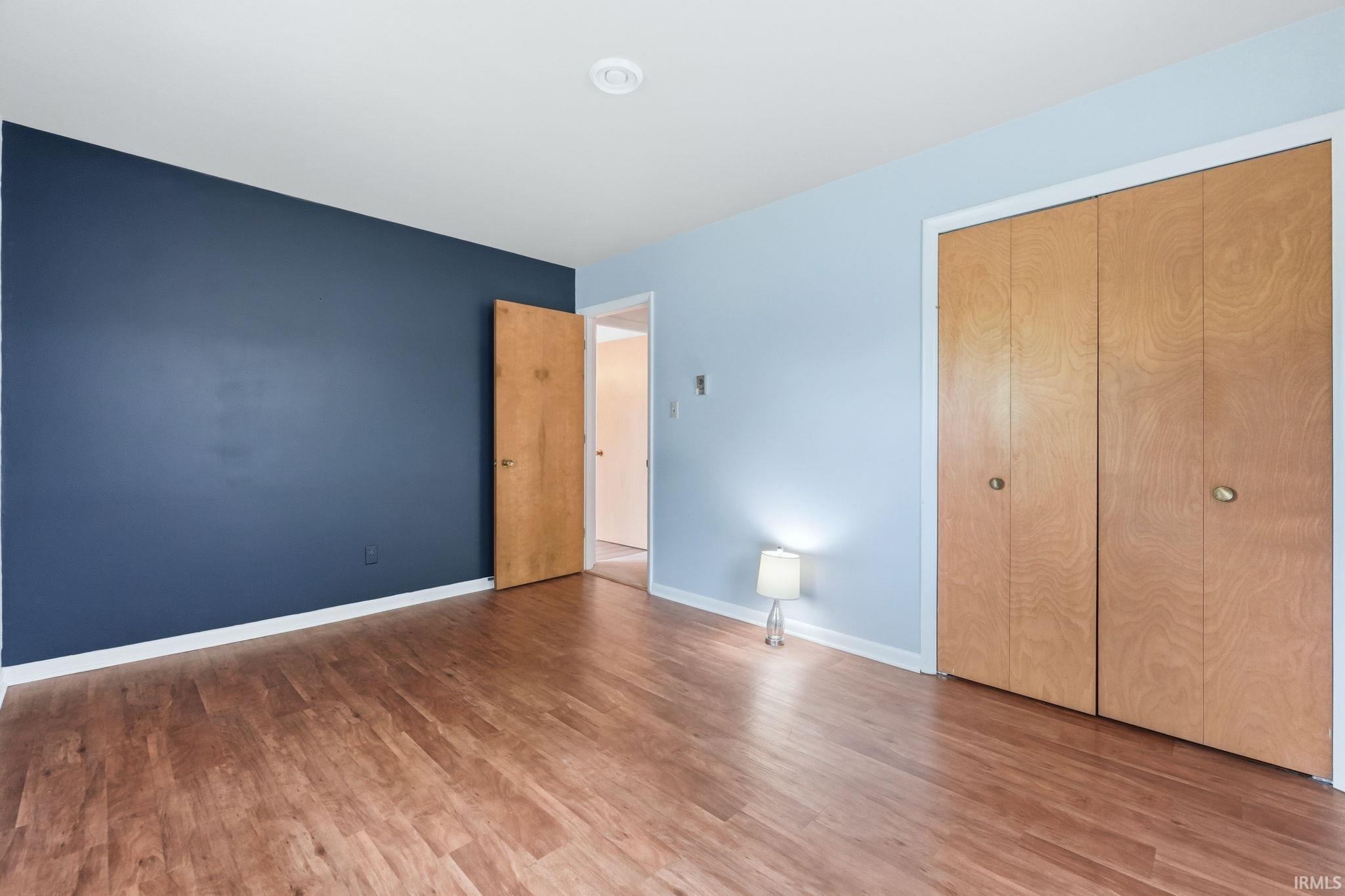 Room featuring wood-finish flooring, a recessed ceiling light, and a two-tone wall treatment with a deep blue accent wall