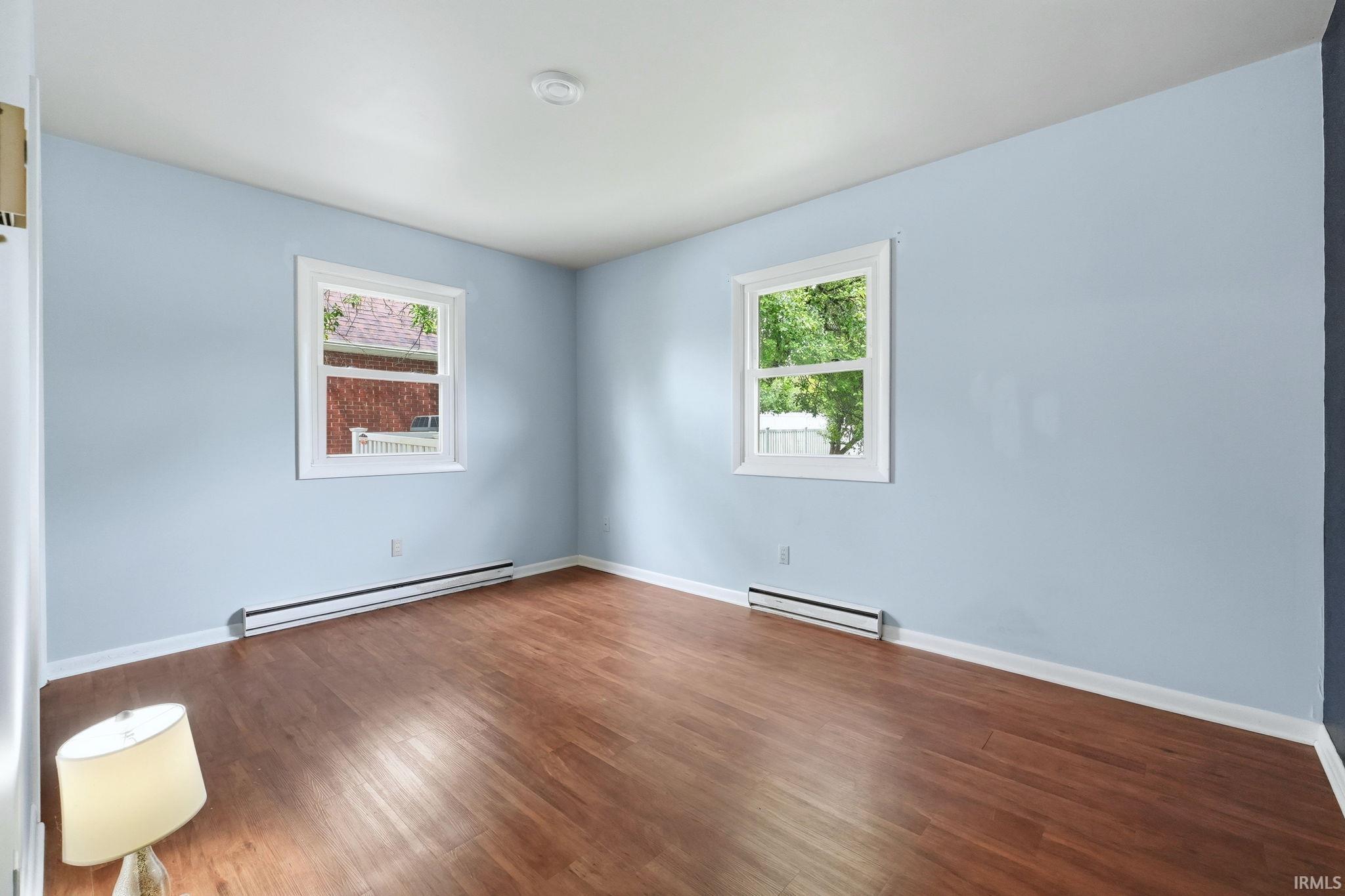 Bright room featuring wood-finish flooring and two windows with white trim