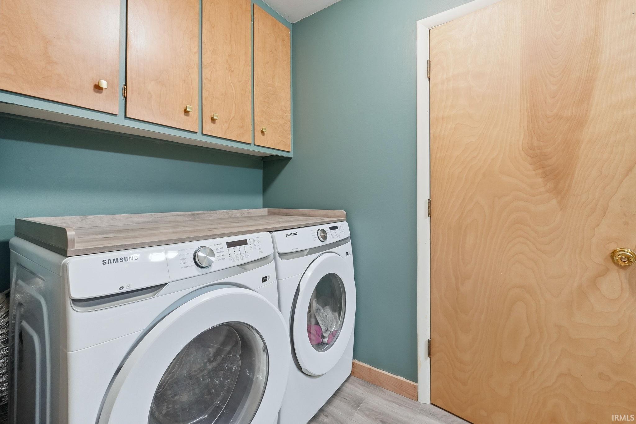 Laundry area featuring wood-finish cabinetry, a light wood-finish countertop, and slate-tone wood-finish flooring