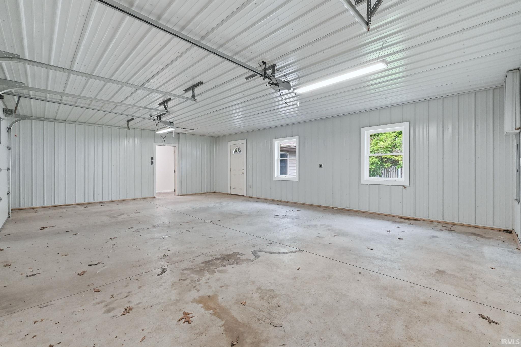Spacious garage featuring a concrete floor, corrugated metal walls, and a corrugated metal ceiling