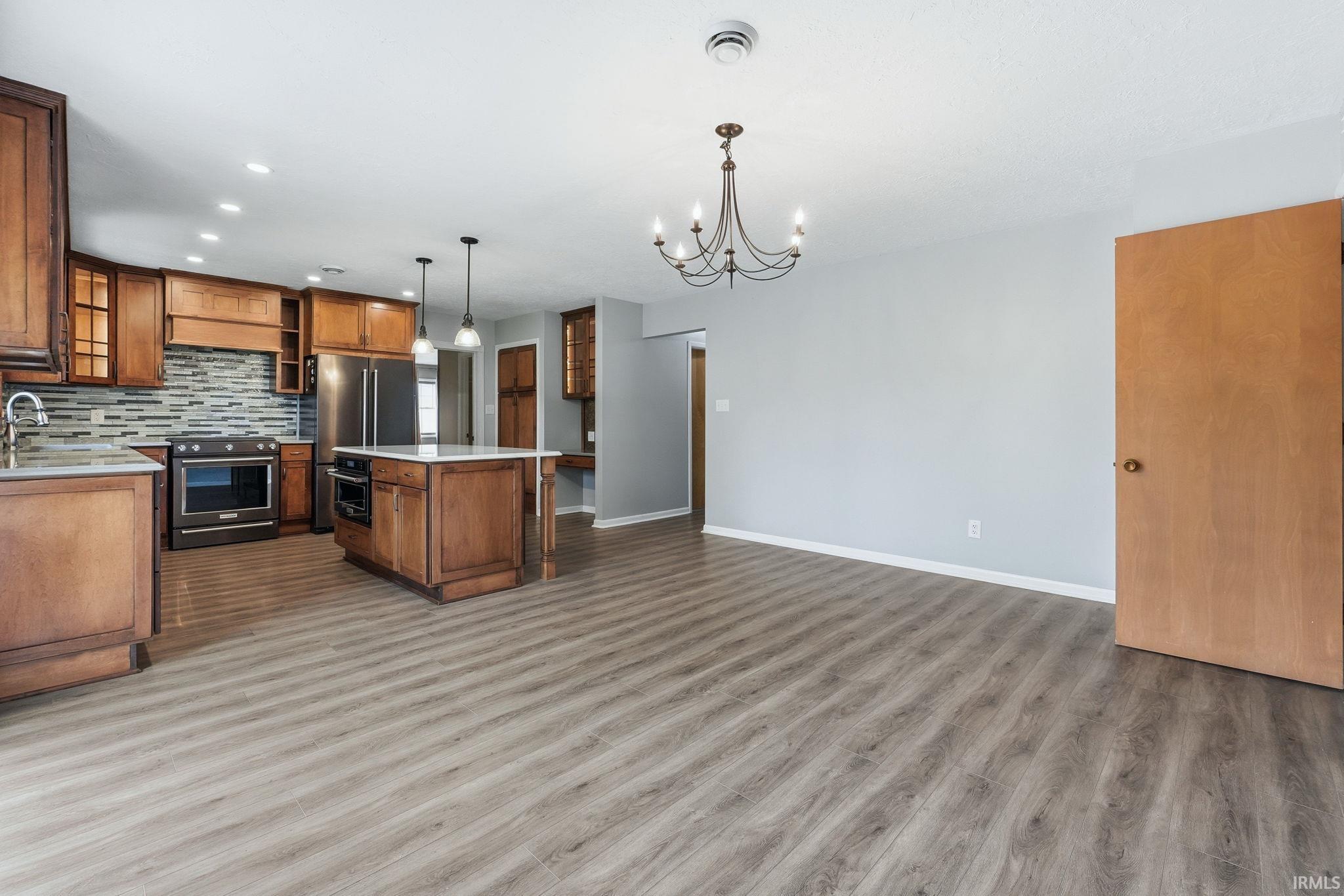 Open-concept kitchen and living area featuring wood-finish flooring, light gray wall paint, and recessed lighting