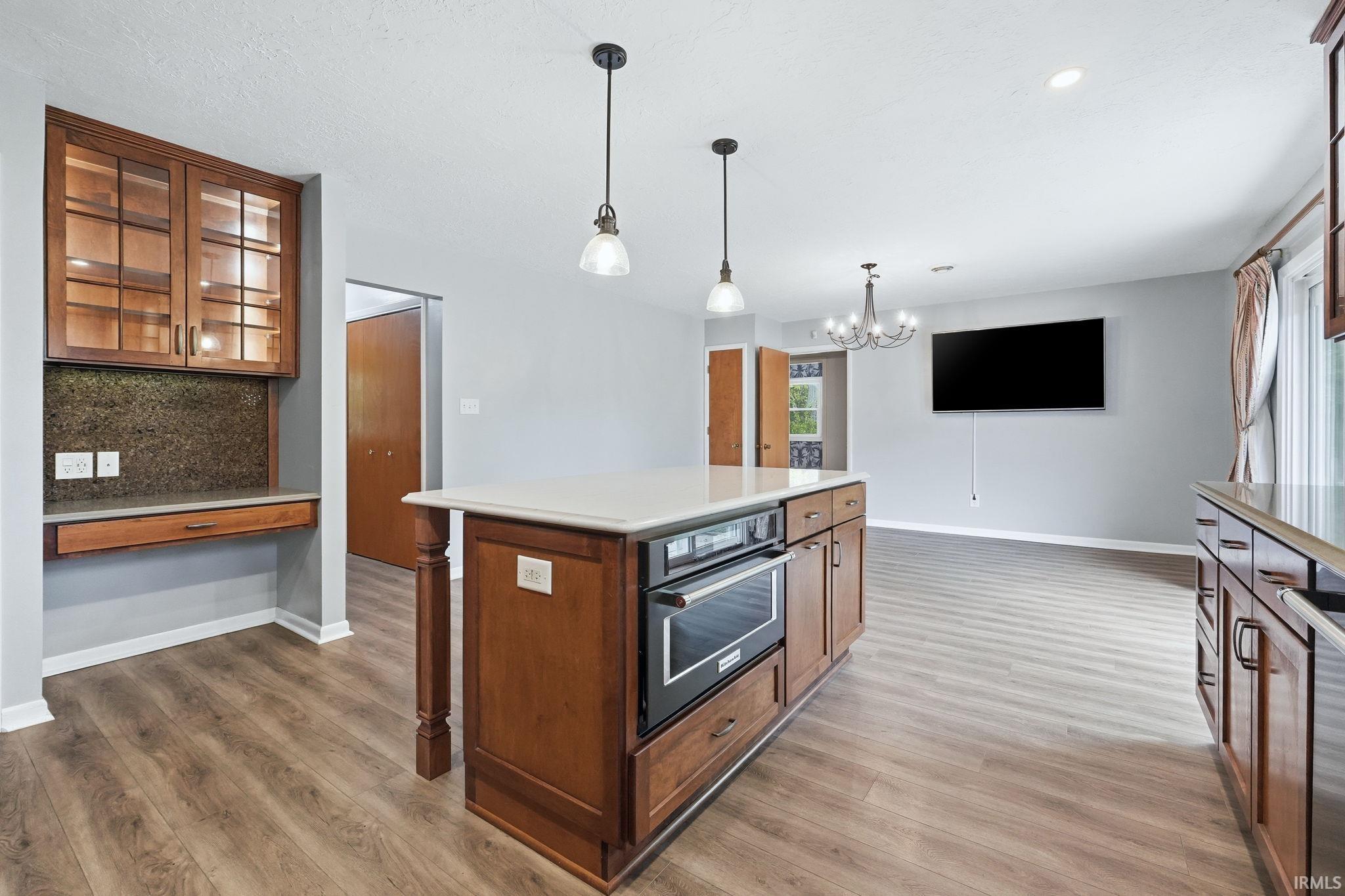 Kitchen island with integrated oven and built-in microwave, complemented by pendant lighting