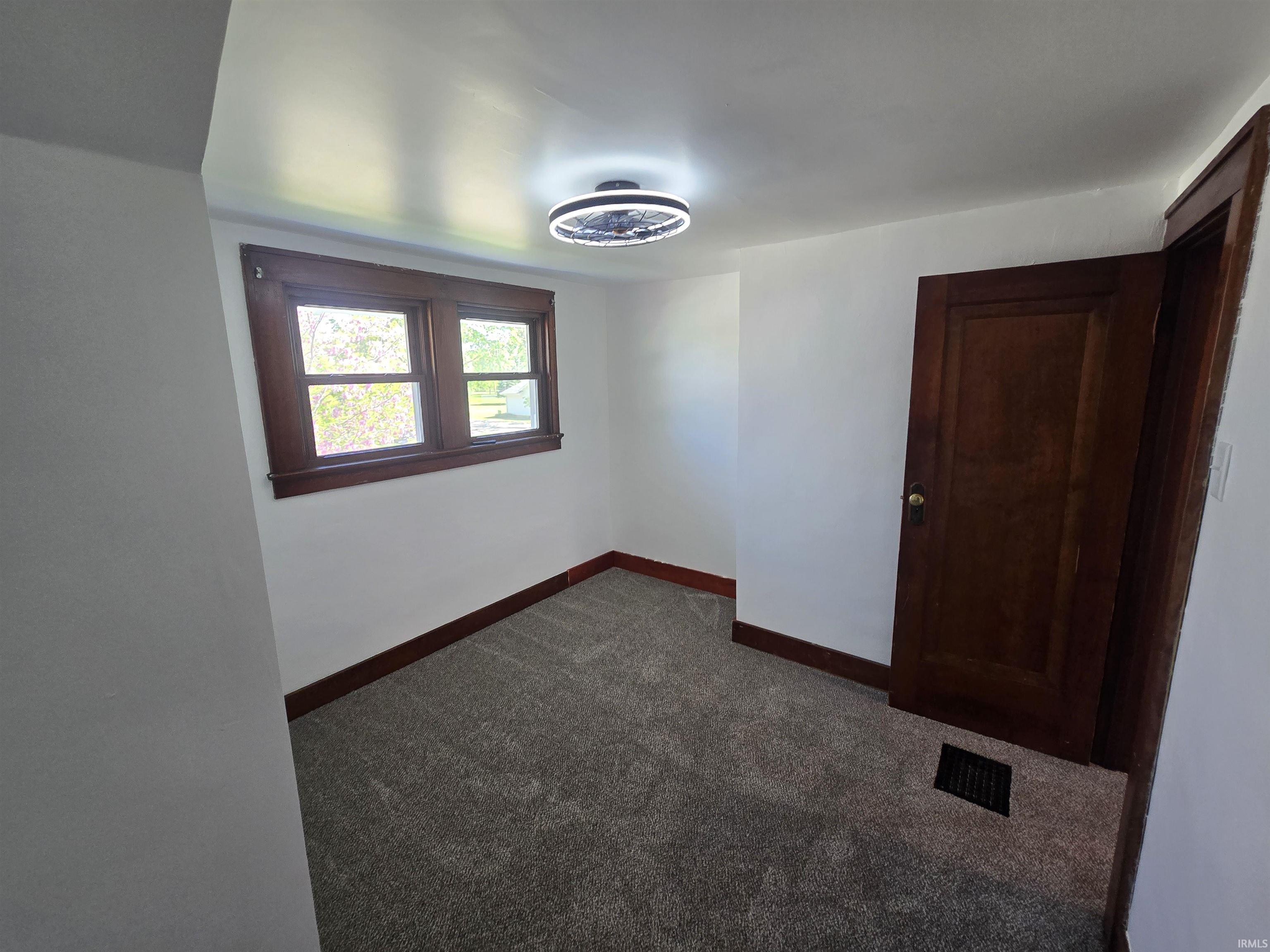 Room featuring gray textured carpeting, white walls, and dark wood trim