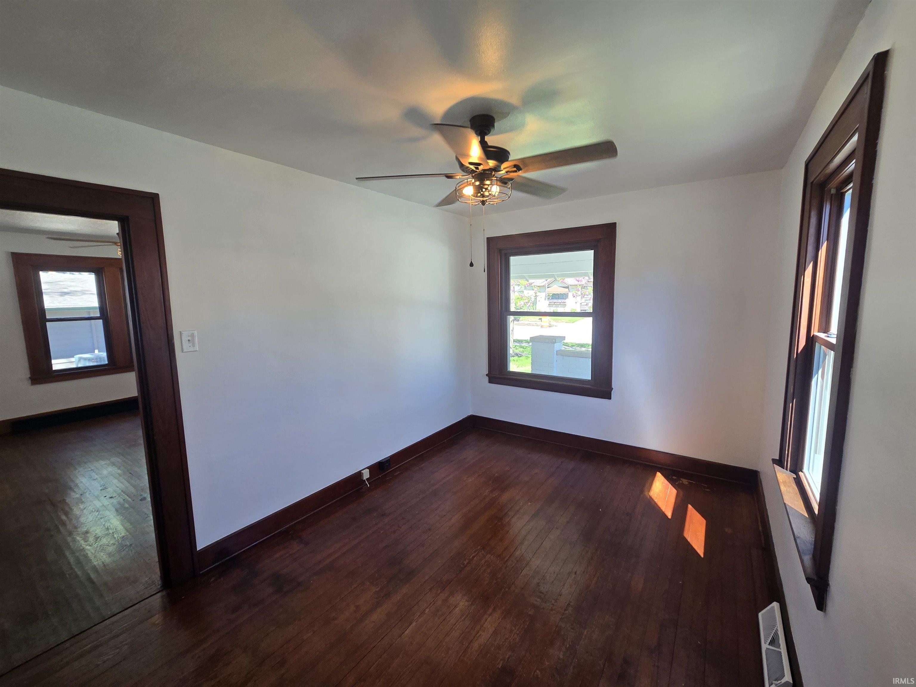 Room featuring wood-finish flooring, white walls, and dark wood trim