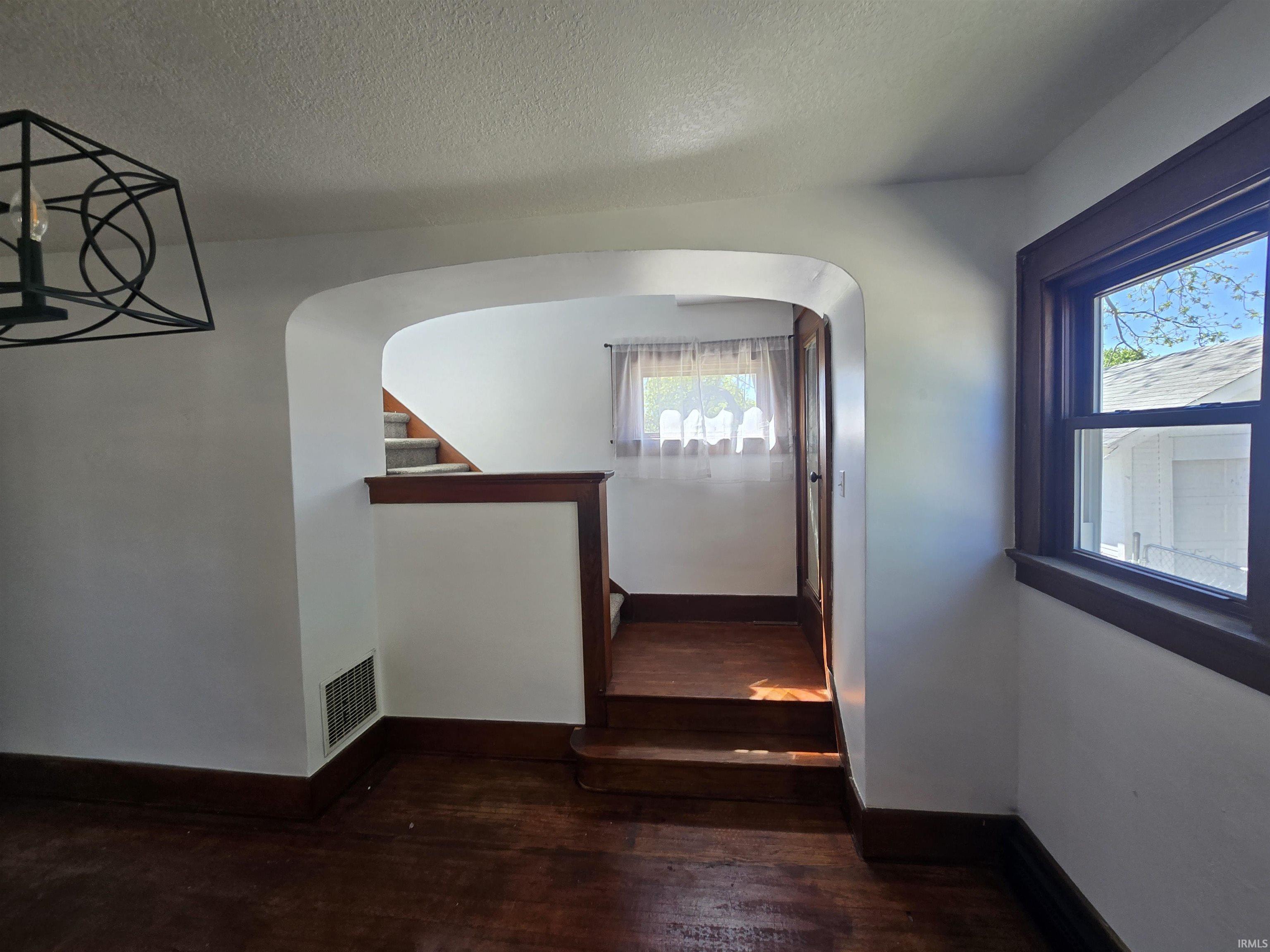 Inviting arched doorway leading to a carpeted staircase