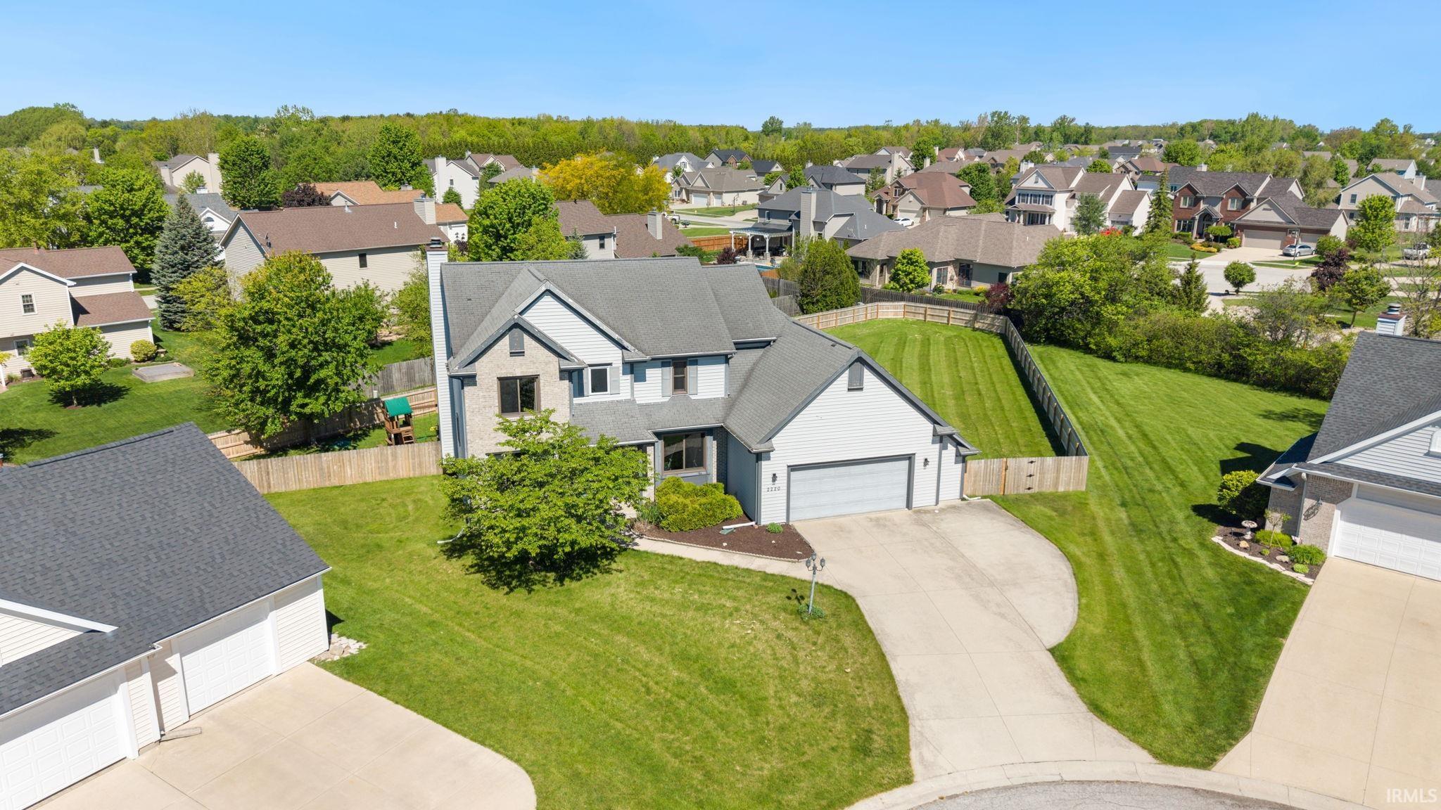 Two-story residence featuring light gray siding with brick accents, an attached two-car garage, and a concrete driveway