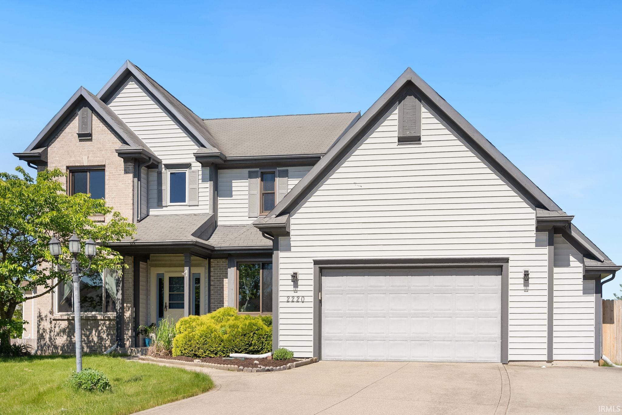 Two-story residence featuring light gray siding and brick accents