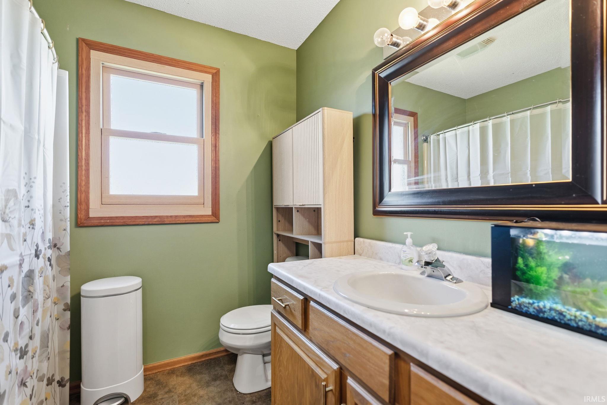 Bathroom featuring a single vanity with a laminate countertop, integrated sink, and wood-finish cabinetry