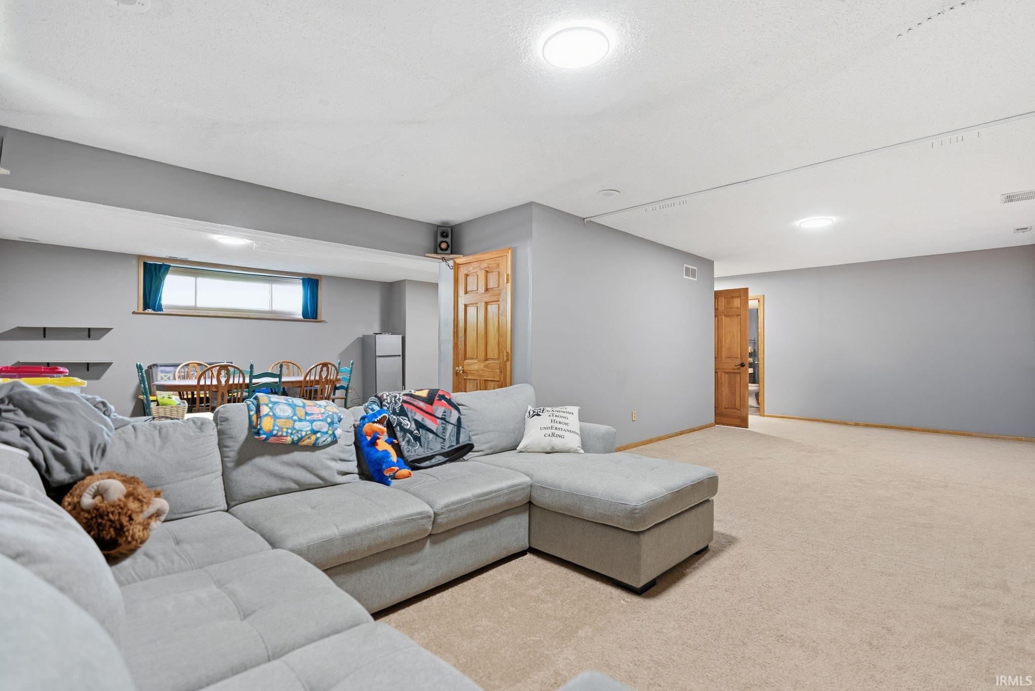 Spacious lower-level room featuring light gray walls, neutral carpet flooring, and recessed lighting