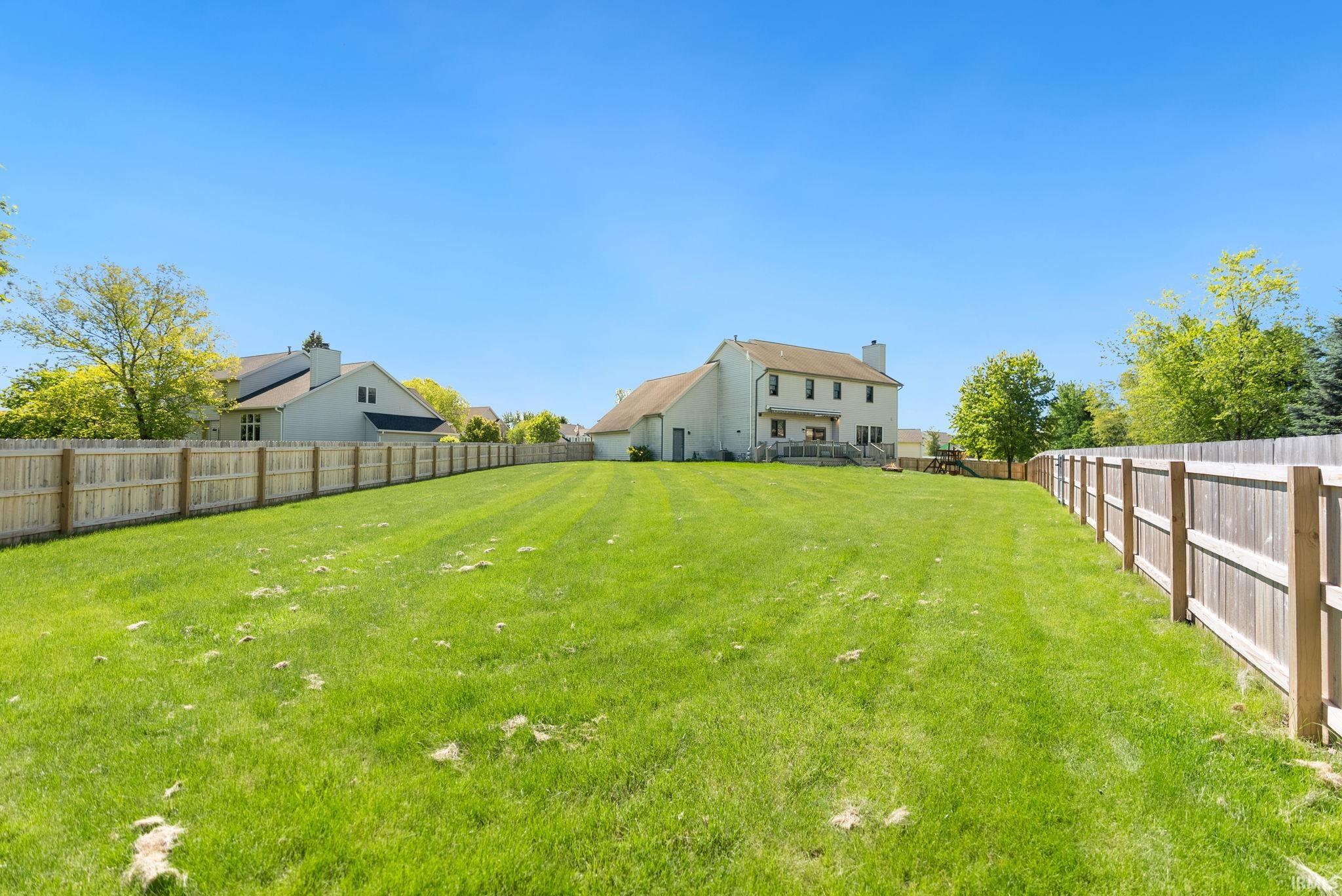 Expansive green lawn with a full wooden privacy fence