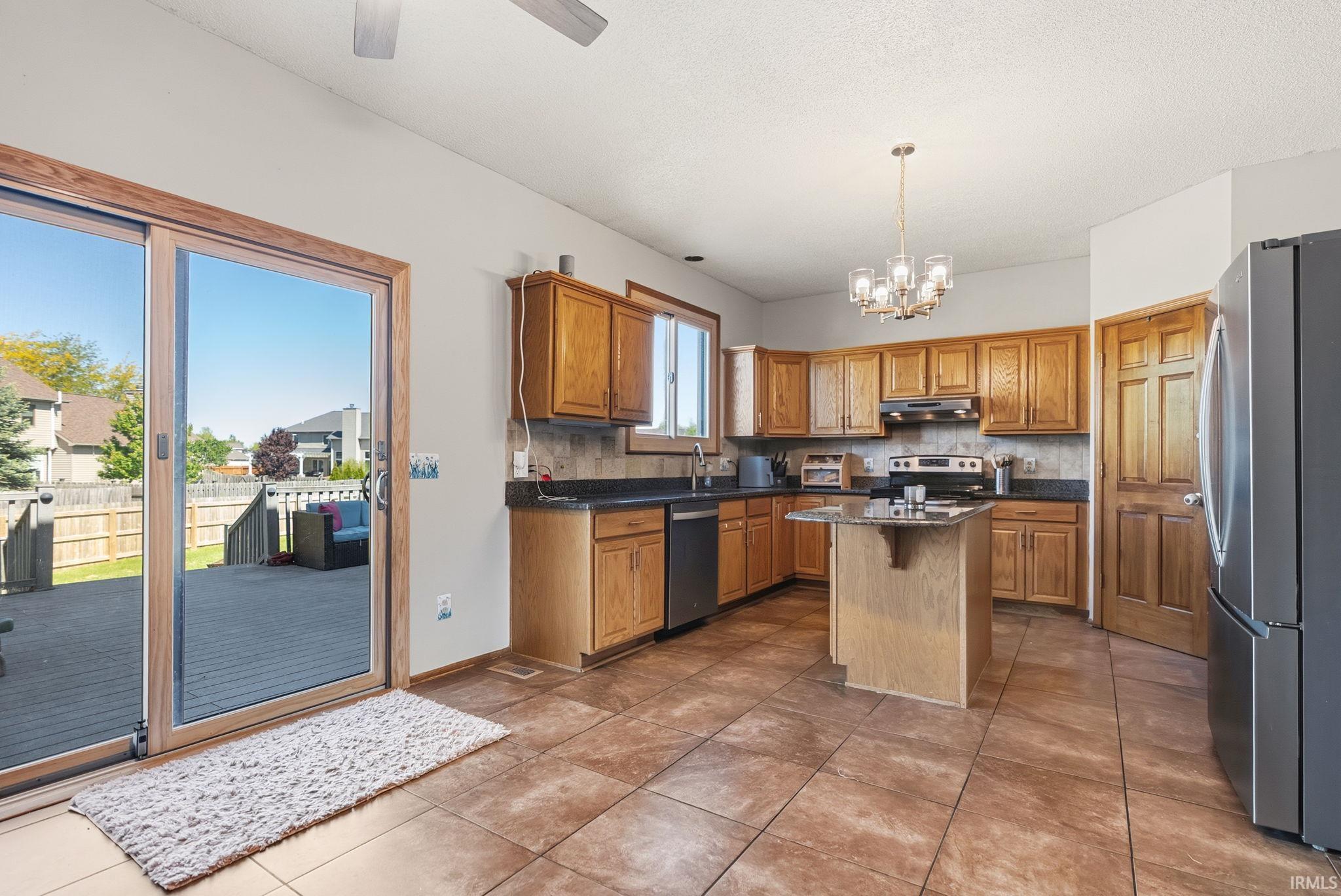 Kitchen featuring wood cabinetry, dark countertops, and a central island with a granite-style surface