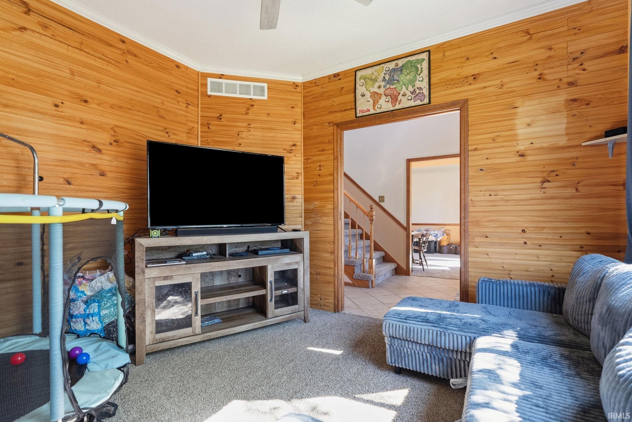 Wood-paneled room with carpeted flooring and white crown molding