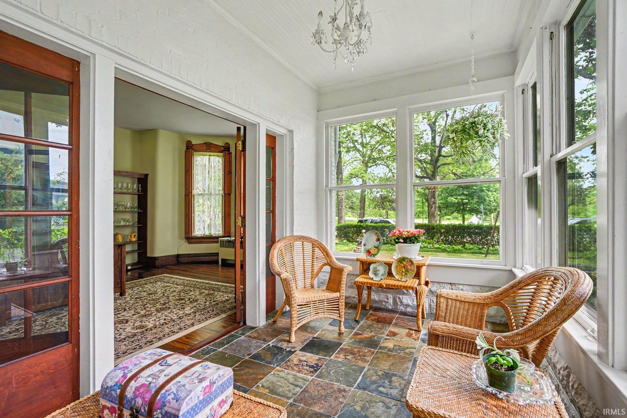 Sunroom featuring multi-toned slate tile flooring and a white beadboard ceiling with a chandelier