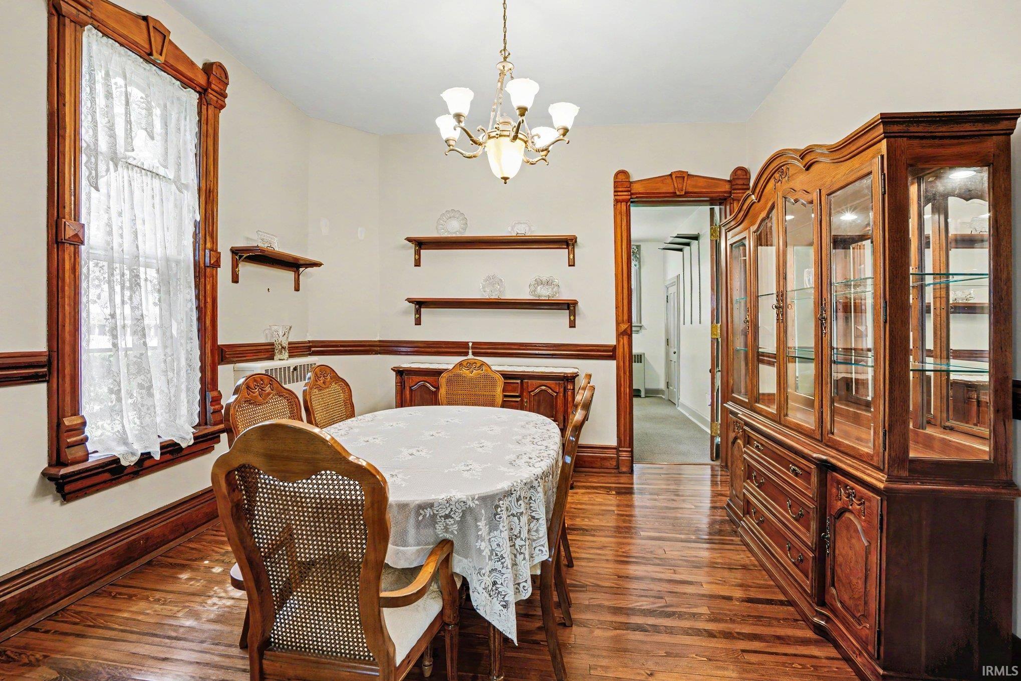 Hardwood flooring featured throughout this room with detailed wood trim framing the window and doorway