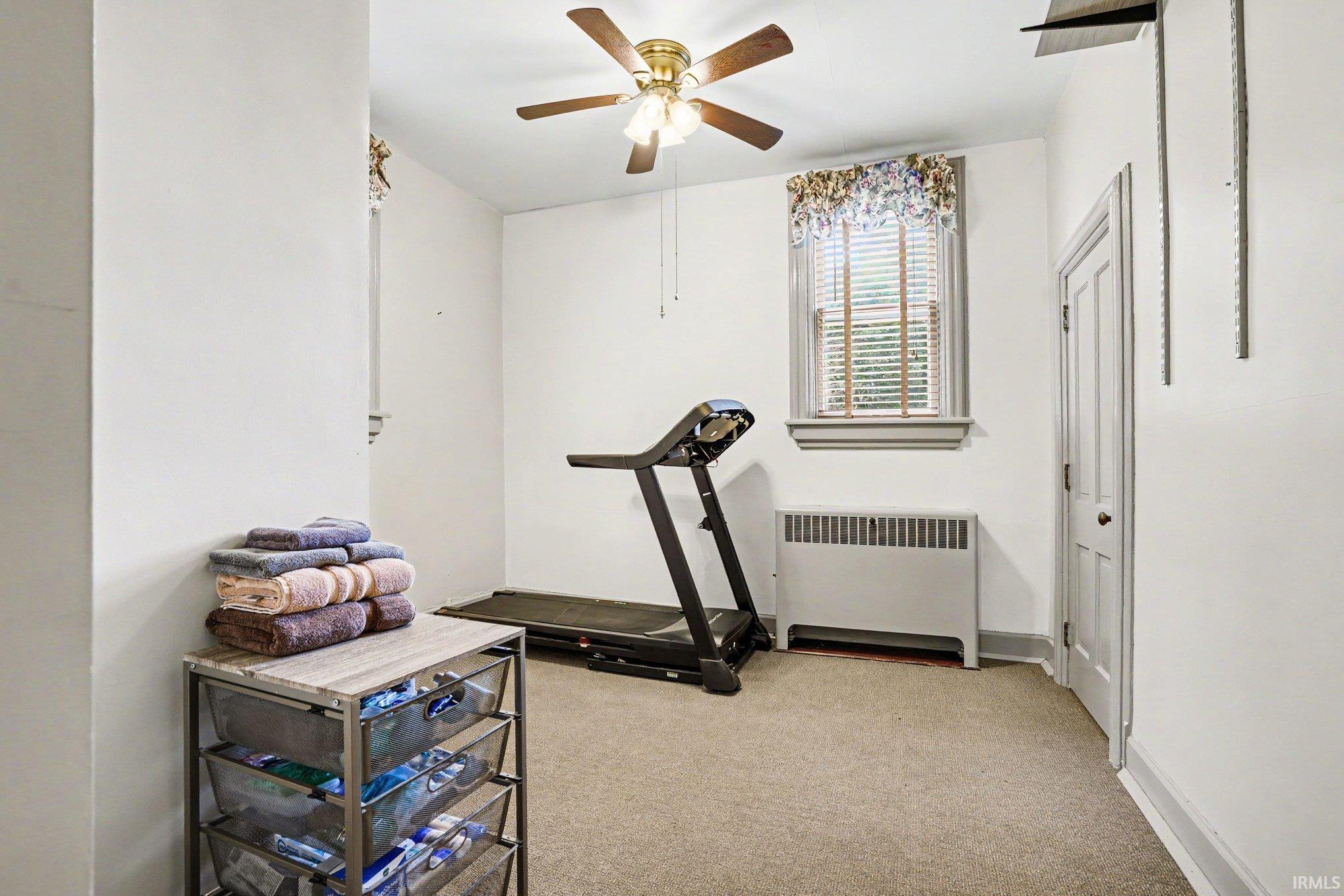 Originally the guest bedroom..Carpeted main floor room featuring a full bath ensuite with a ceiling fan, window with blinds, baseboard heating unit, and a paneled door