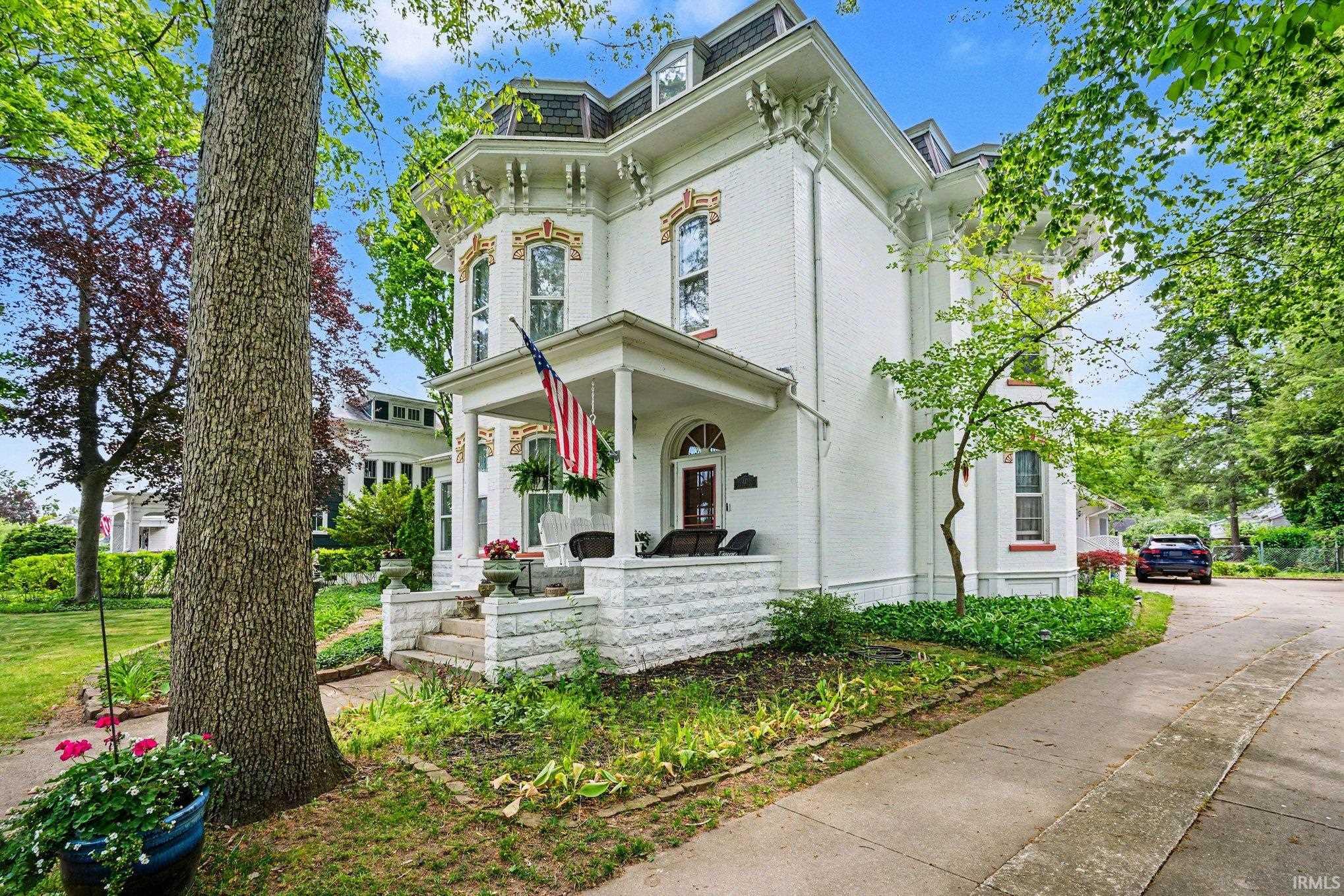White brick exterior featuring intricate architectural detailing and a covered front porch