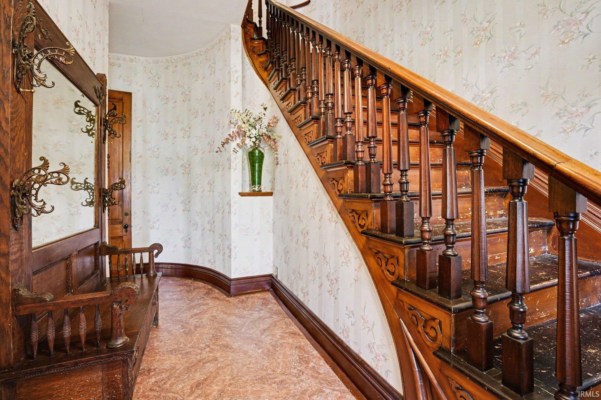 Grand staircase featuring carved wood balusters and a rich wood handrail