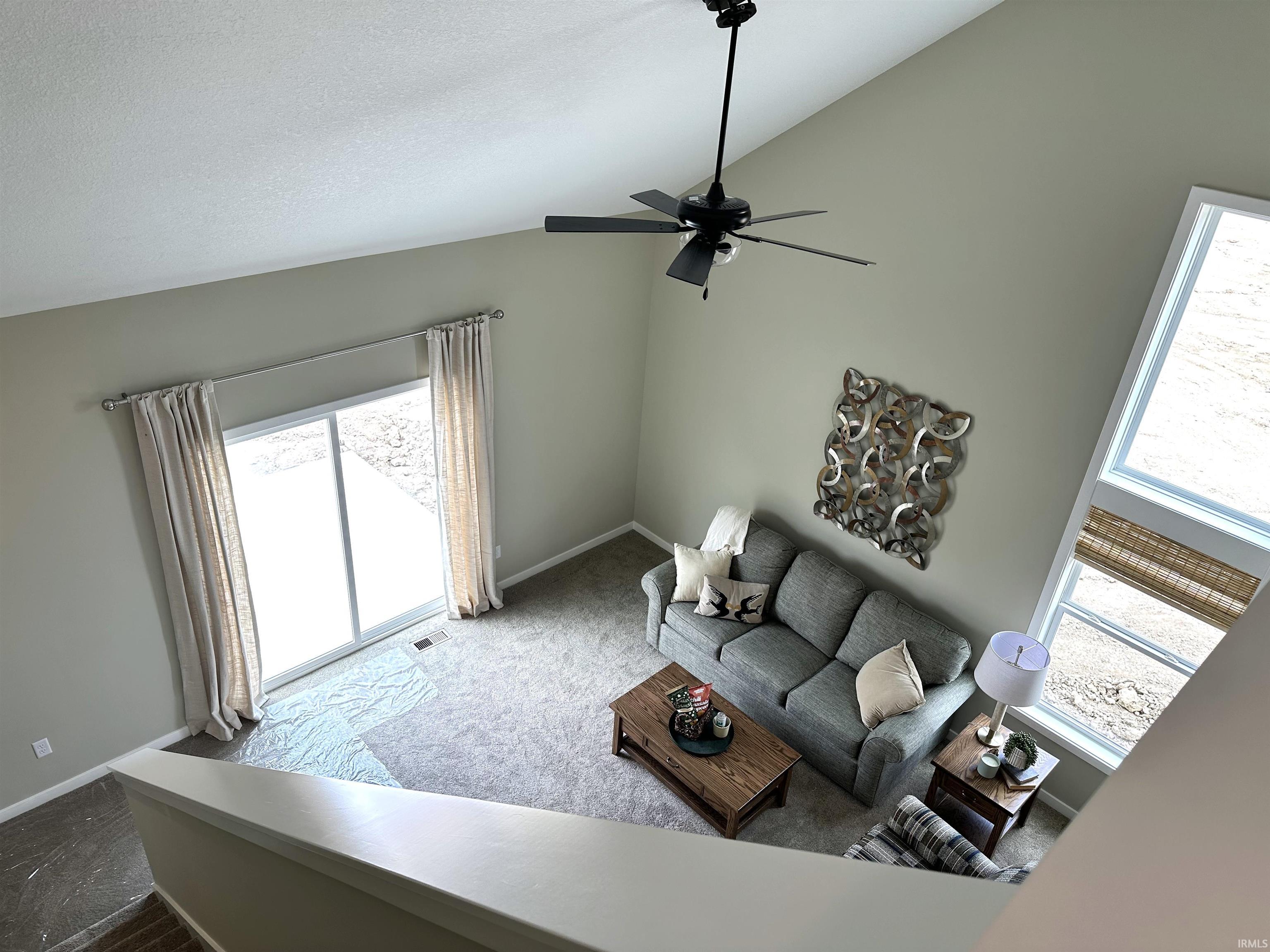 Two-story living area featuring a vaulted ceiling and an overhead ceiling fan