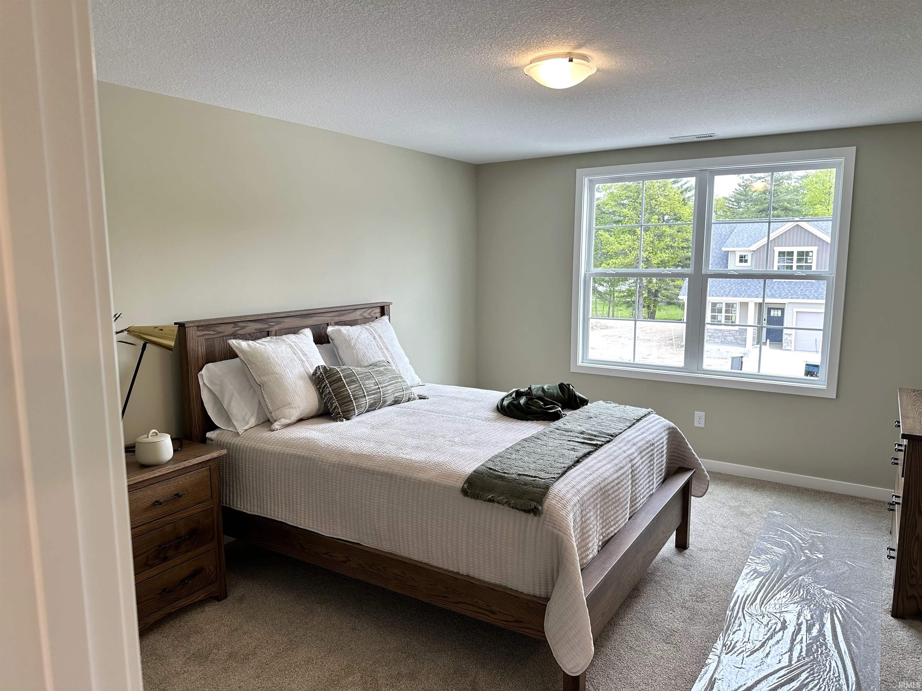 Bedroom featuring a large window with white trim, light-toned walls, and a ceiling-mounted light fixture