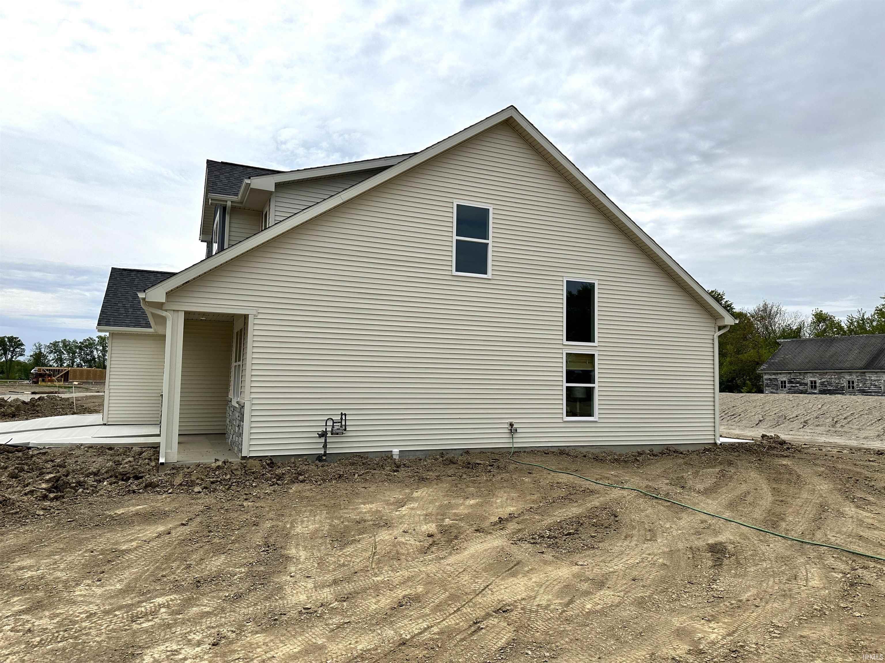 Contemporary new construction featuring a light-colored vinyl siding exterior, dark shingle roofing, and white-framed windows