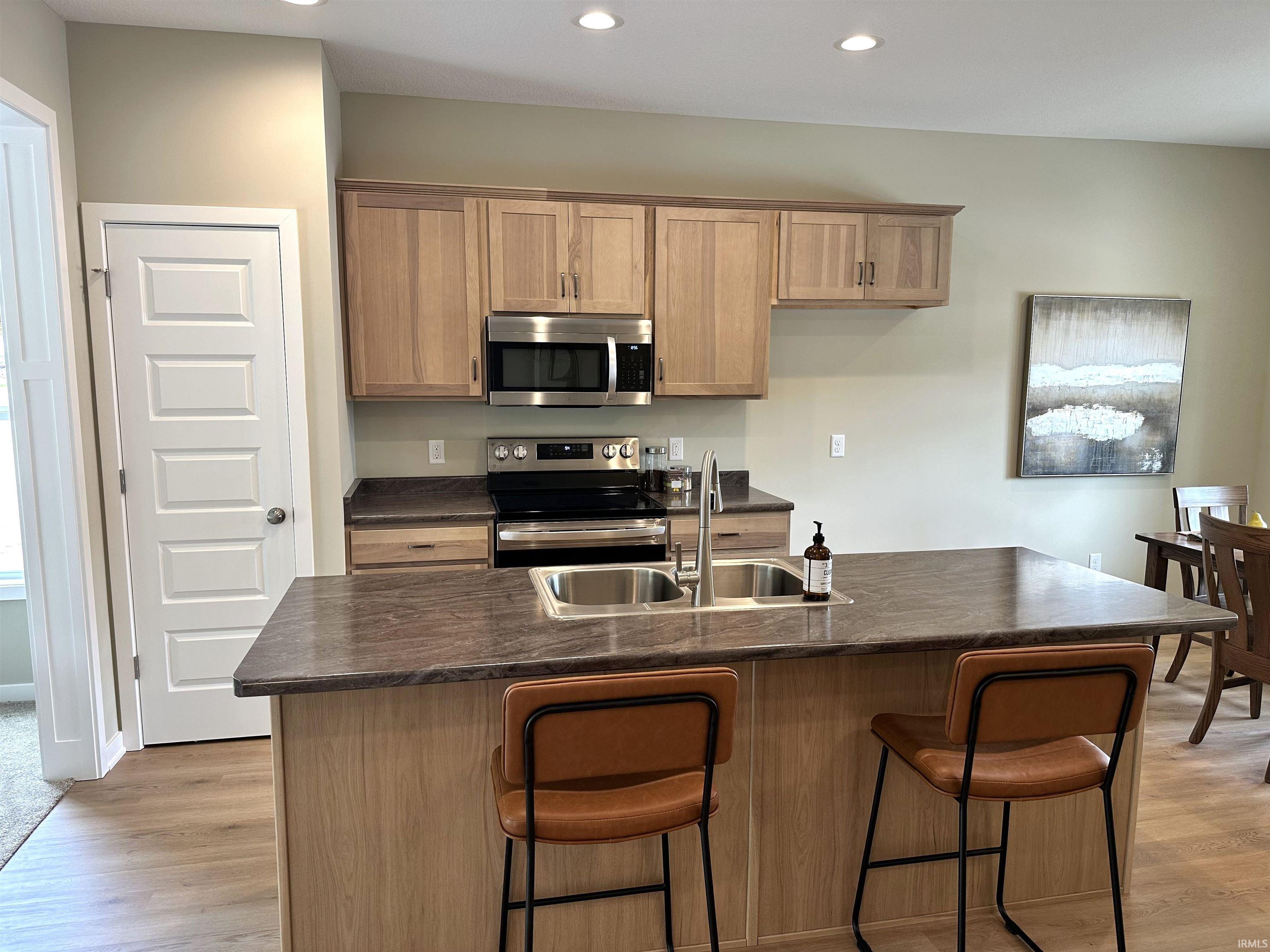 Kitchen featuring a large central island with an integrated double basin stainless steel sink and a single-handle faucet