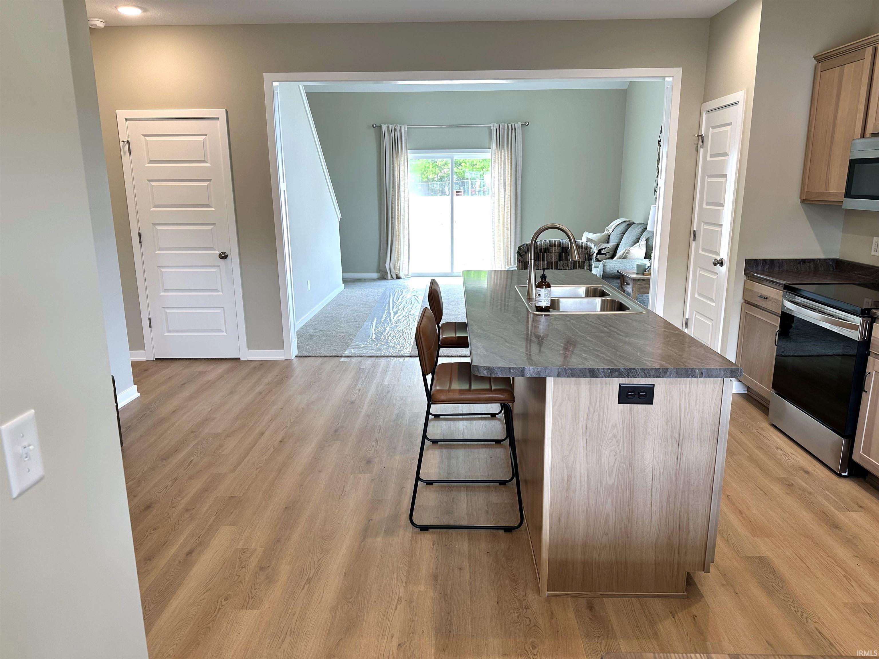 Contemporary kitchen island featuring a deep undermount sink, gooseneck faucet, power outlets, and stone-finish countertop