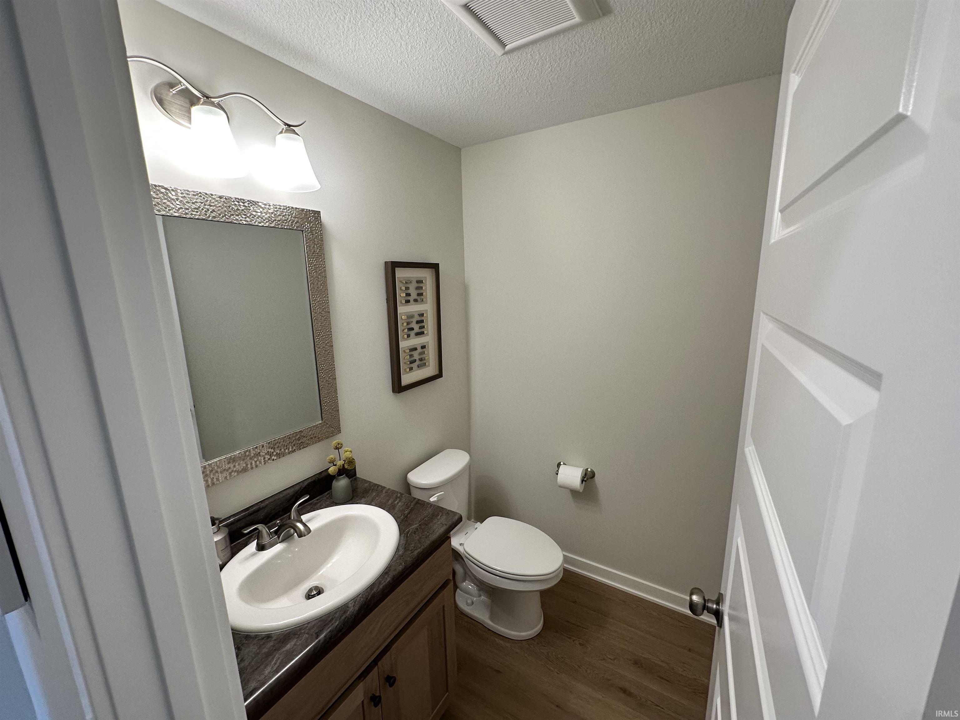 Half bathroom featuring a vanity with a dark countertop, an undermount sink, and a brushed nickel faucet