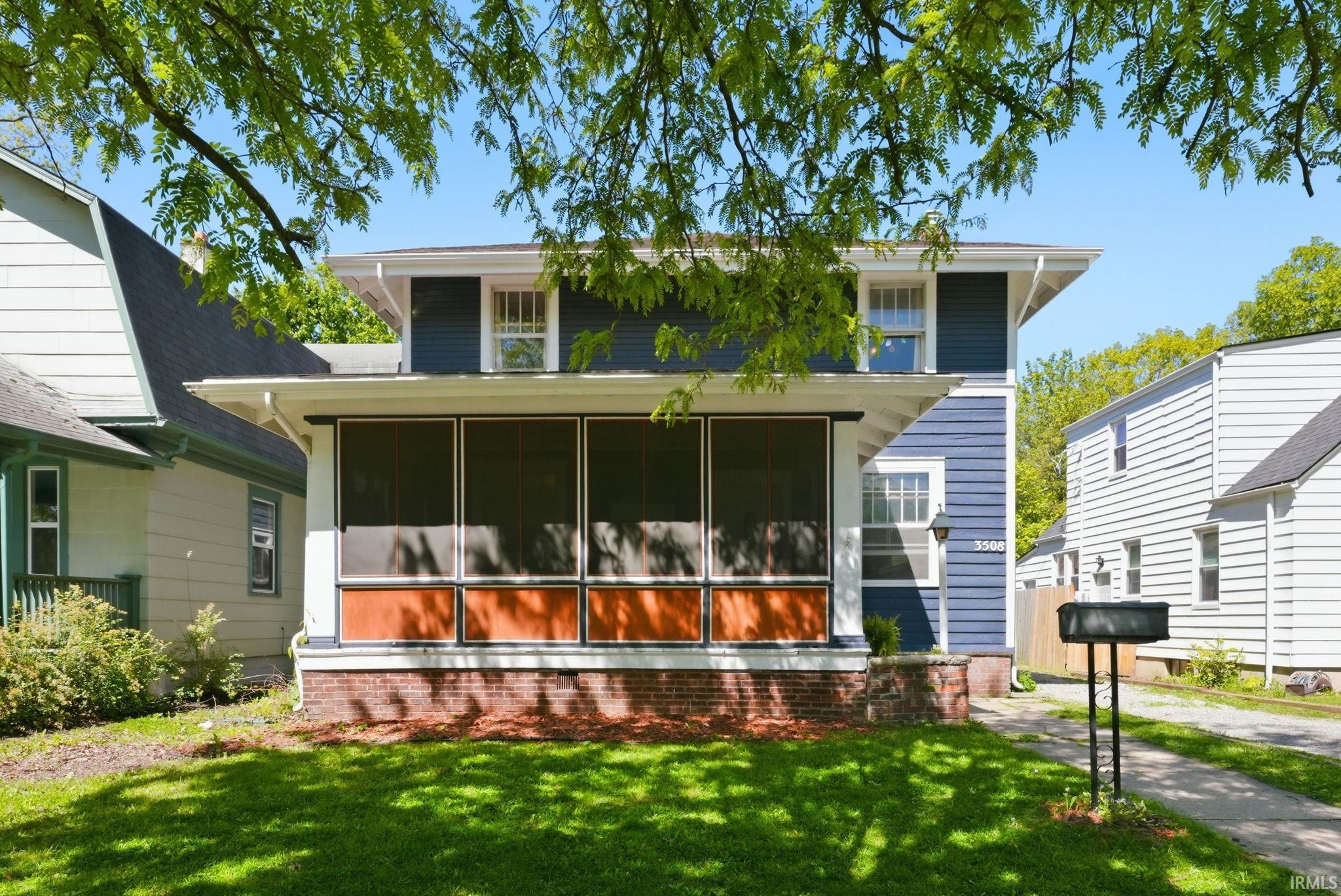 Charming blue siding home featuring a screened front porch with brick foundation detail