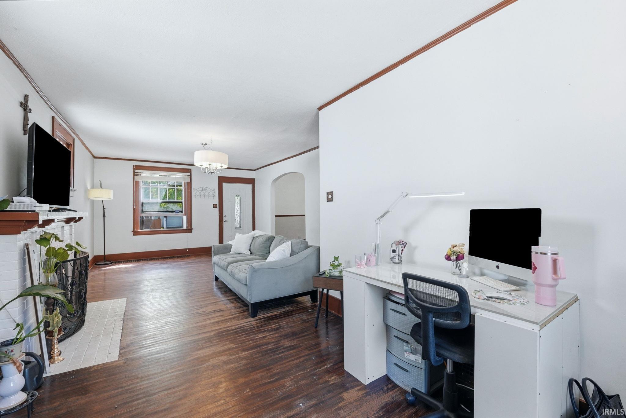 Hardwood flooring extends throughout this expansive room, featuring white walls with dark wood trim