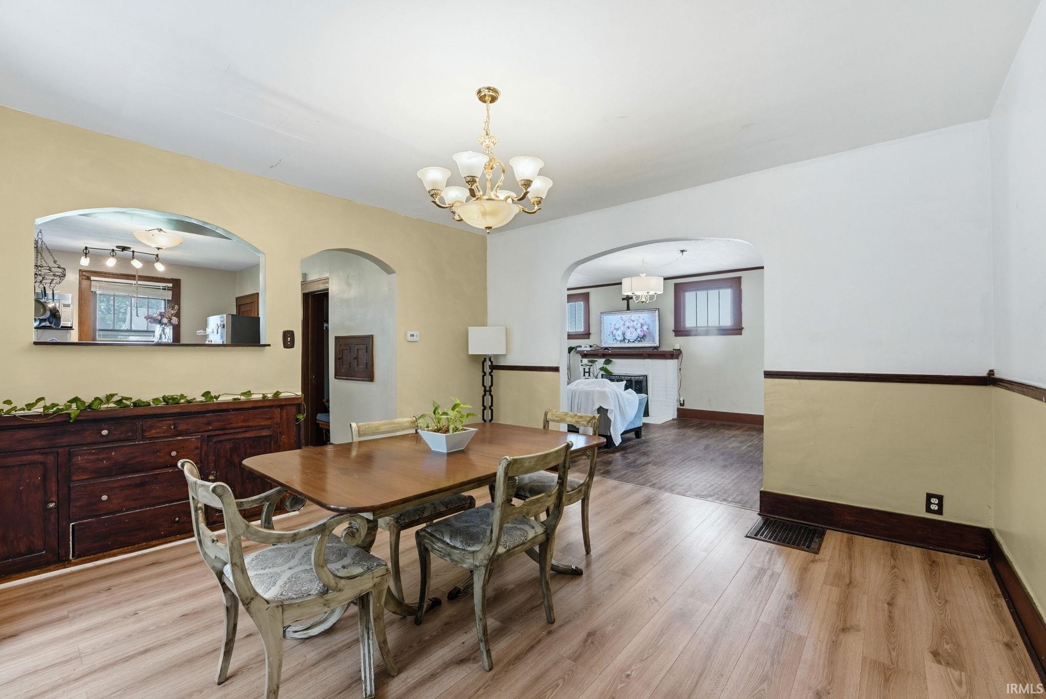 Dining area featuring wood-finish flooring, a decorative chandelier, and a built-in buffet with an arched pass-through to the kitchen