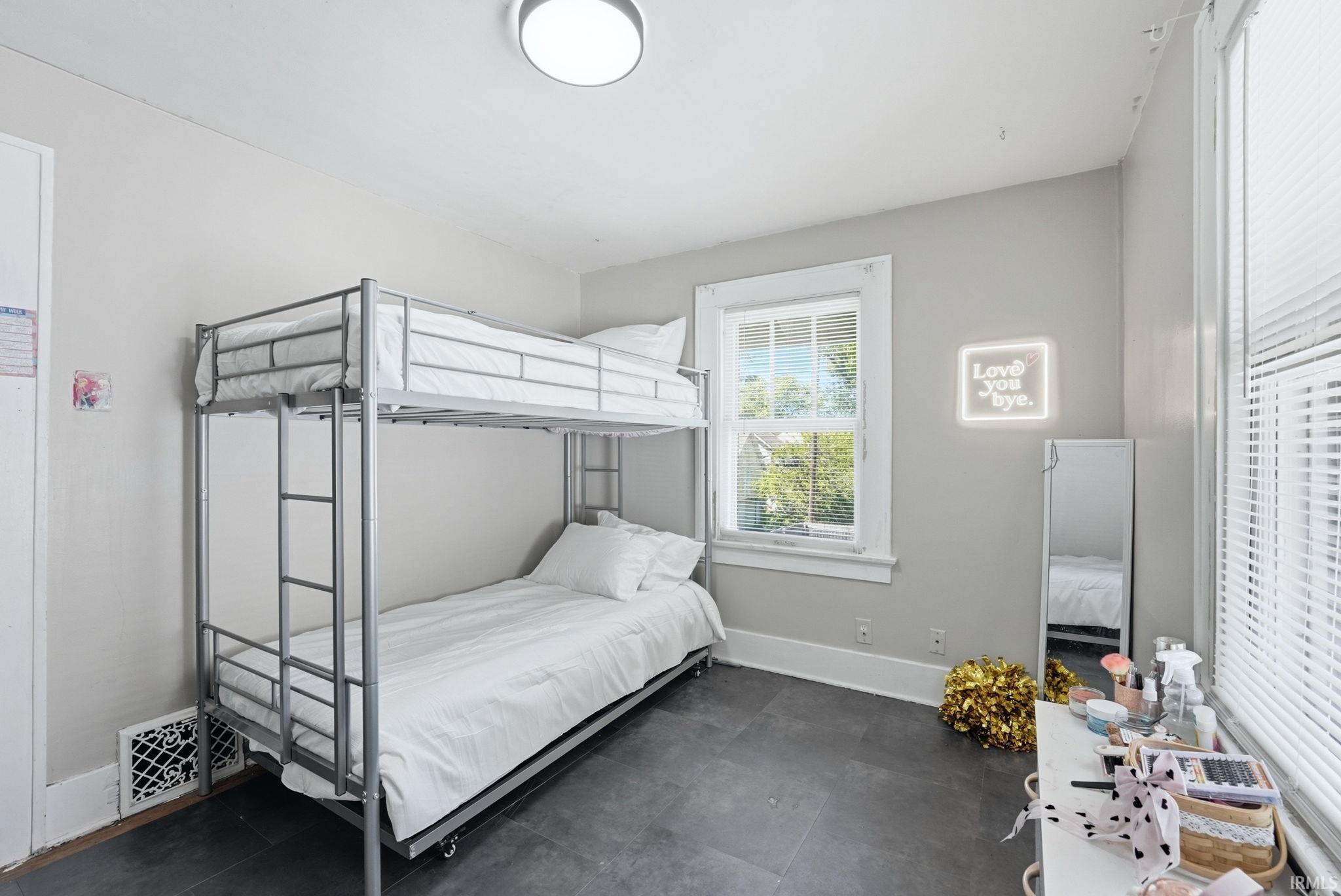 Spacious room featuring neutral painted walls, dark tile flooring, a double window with white blinds, and a flush-mount ceiling light fixture