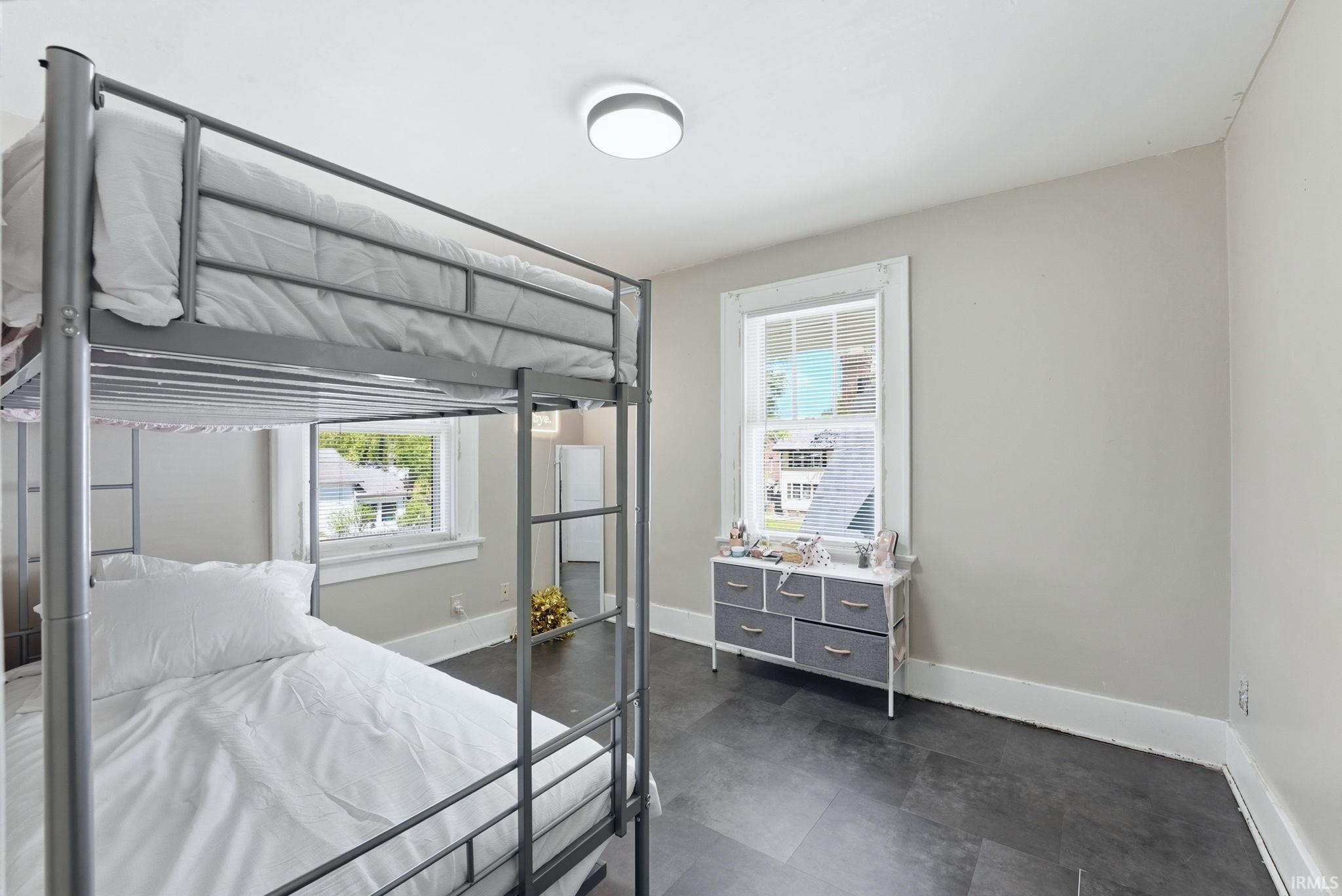 Spacious room featuring dark tile flooring, light neutral wall paint, and white trim