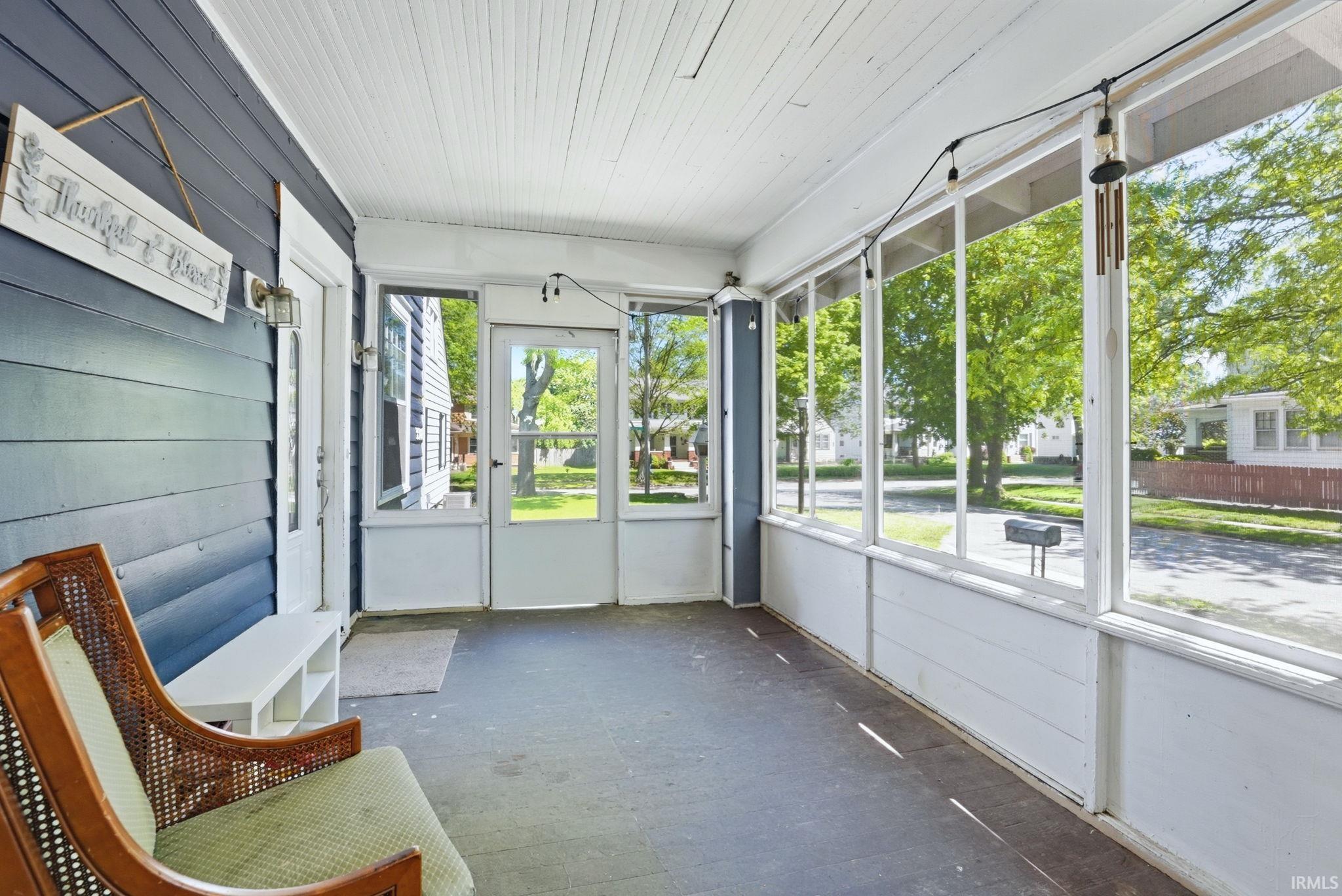 Expansive screened porch featuring a paneled ceiling, wood-finish flooring, two exterior doors, and multiple screen panels