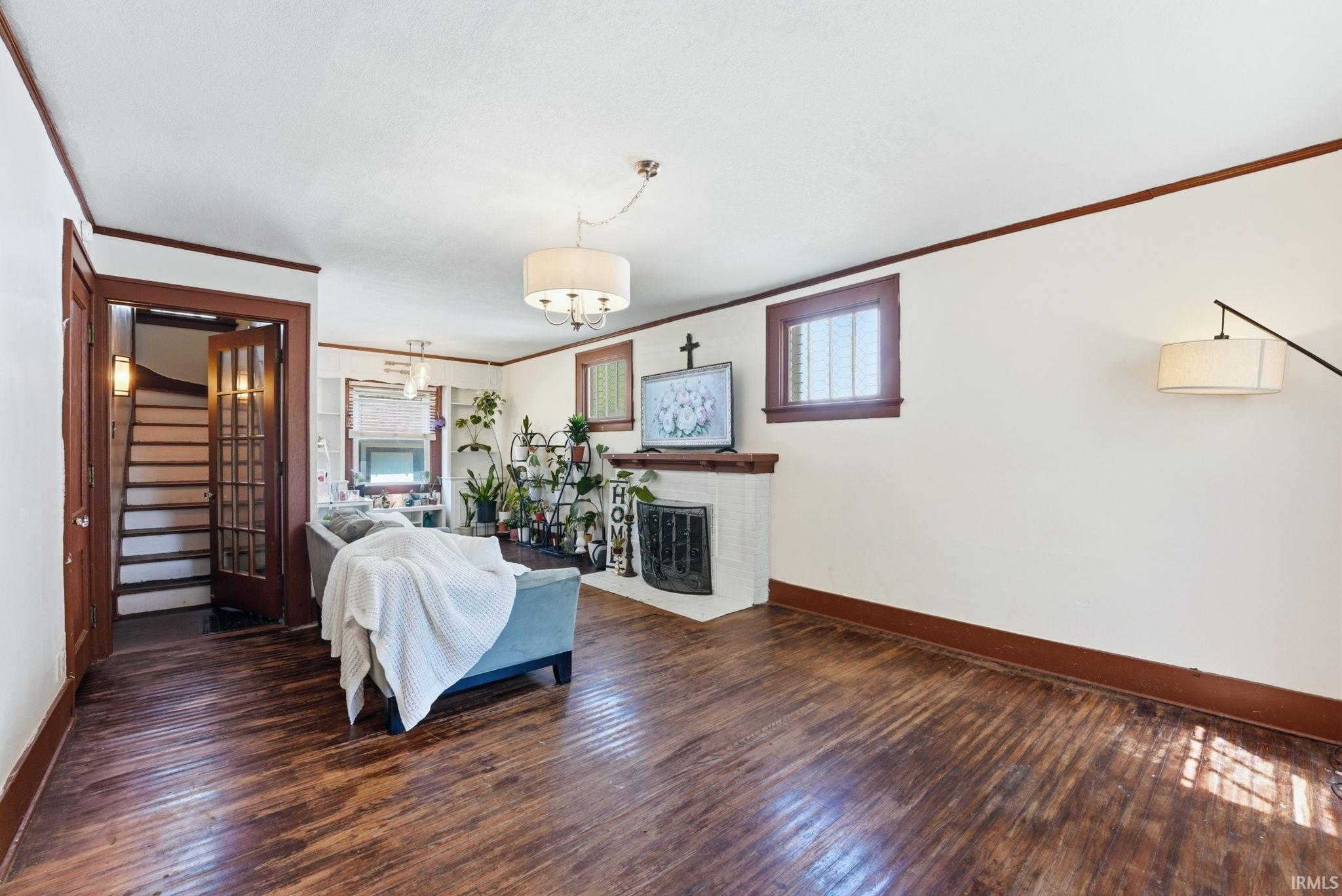 Spacious living area featuring wood-finish flooring, a white tile fireplace surround, and dark wood trim