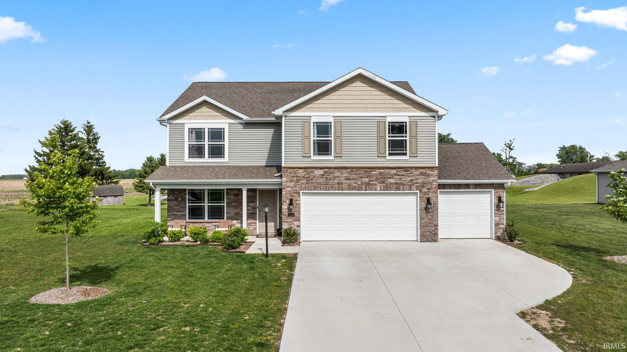 Two-story residence featuring a combination of horizontal siding, stone veneer accents, and gabled rooflines