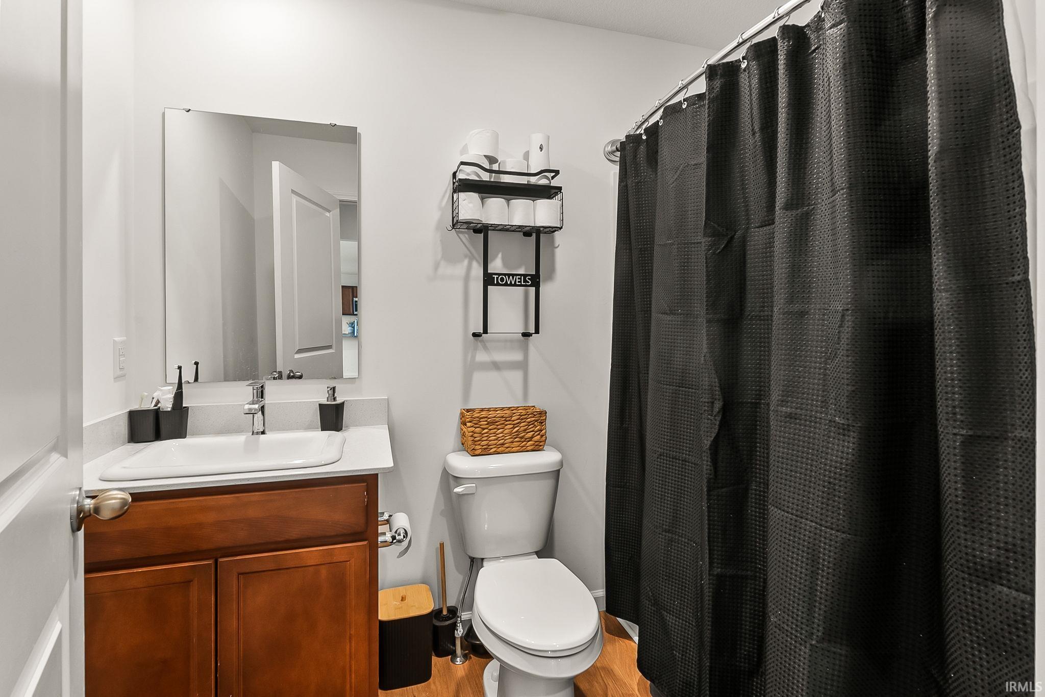 Bathroom featuring a single vanity with a white countertop, undermount sink, and wood-finish cabinetry