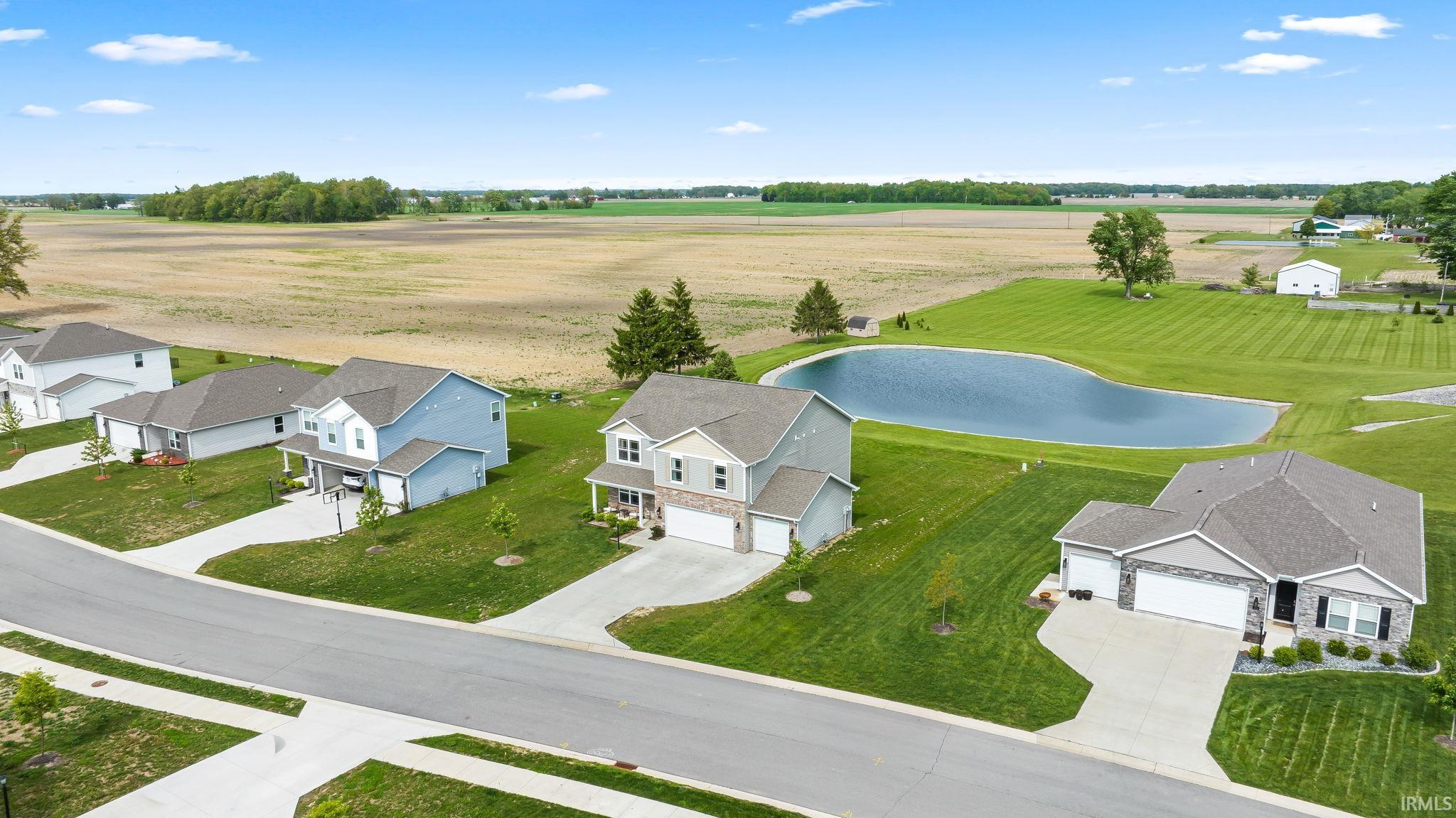 Residential street with three distinct properties, each featuring a private driveway, attached garage, and manicured lawn