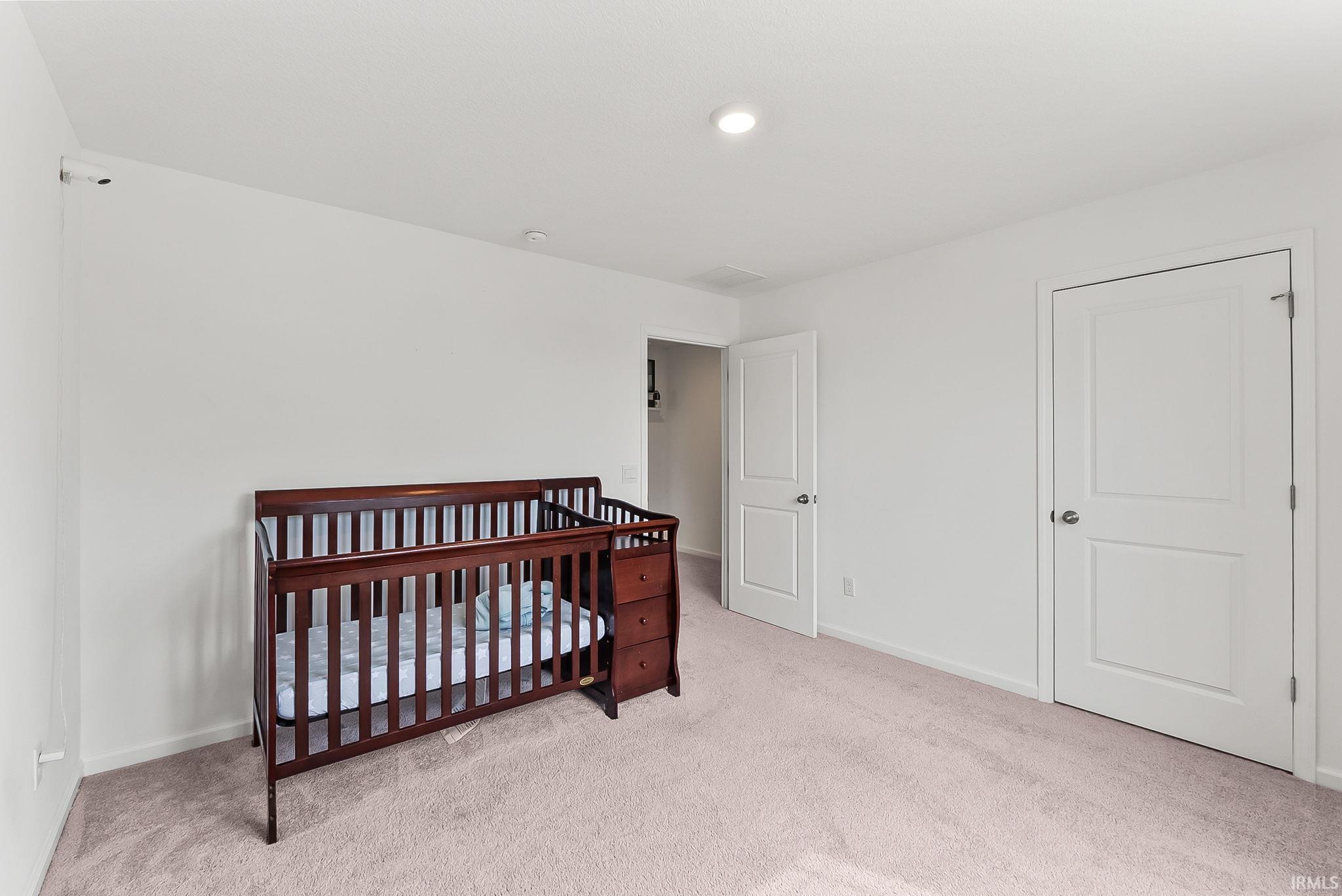 Carpeted interior room featuring white walls, two white panel doors, and recessed ceiling lighting