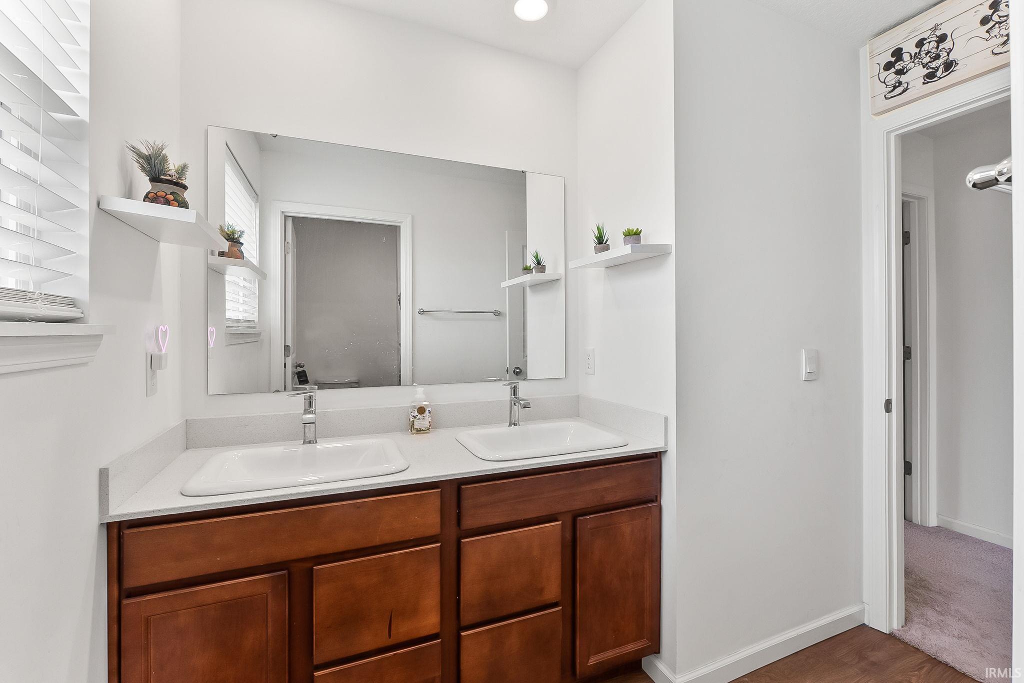 Dual vanity featuring white integrated sinks, chrome faucets, and wood-finish cabinetry