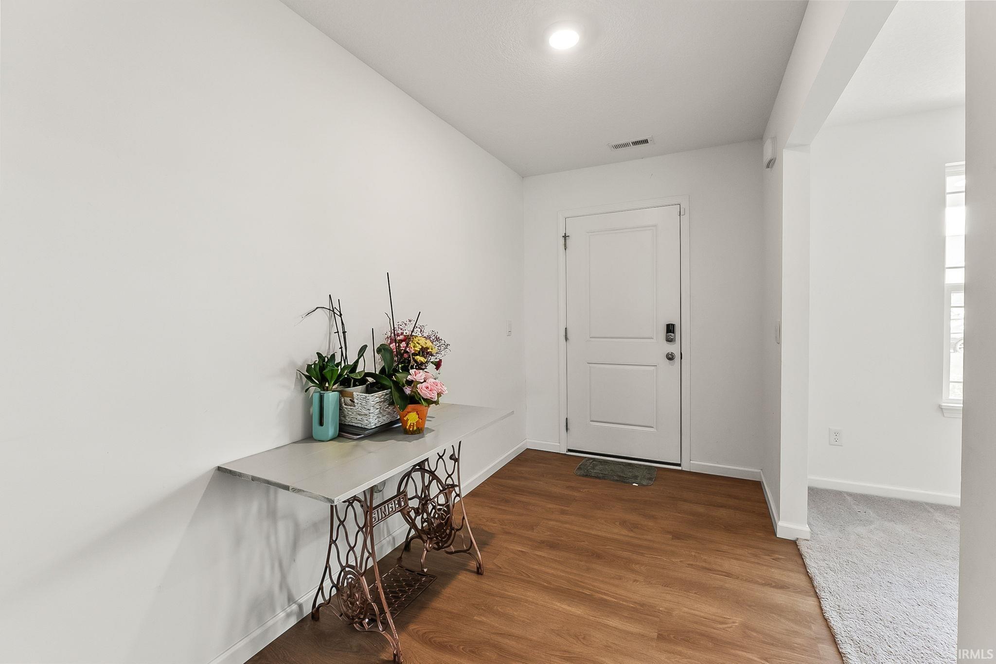 Entryway featuring wood-finish flooring, a white paneled door, and a recessed ceiling light