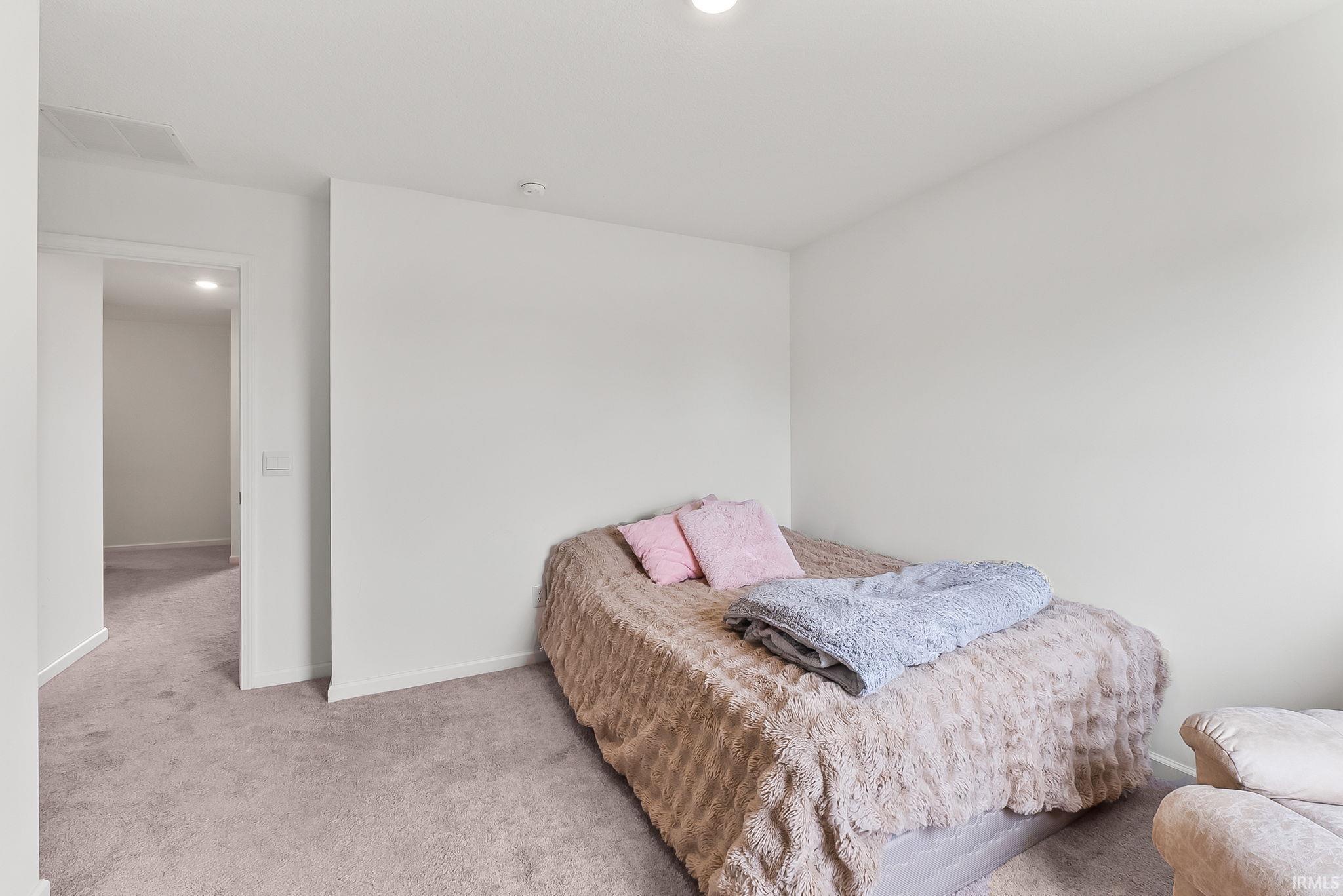 Carpeted room with recessed lighting and a doorway leading to a carpeted hall