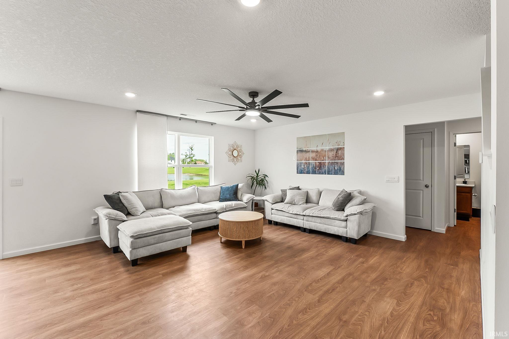 Spacious room featuring wood-finish flooring, recessed lighting, and a contemporary ceiling fan