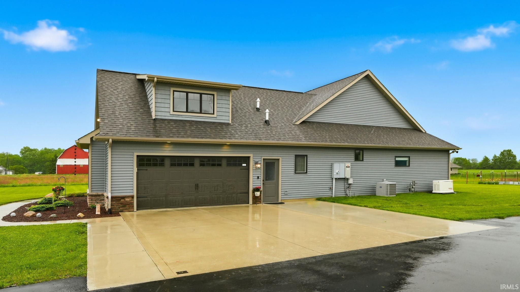 Contemporary two-car garage with a dark panel door, complemented by light gray siding and a stone-clad foundation