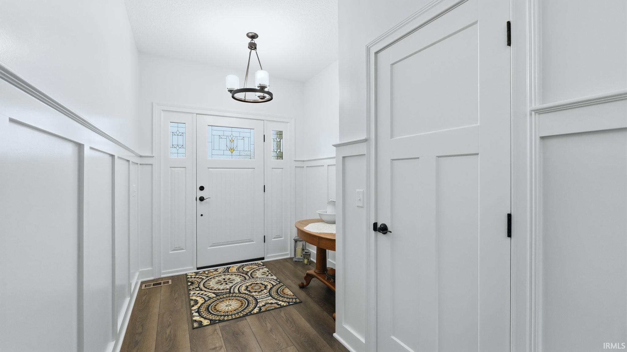 Entryway featuring a decorative front door with transom and sidelight windows, board and batten wainscoting, and a contemporary ceiling light fixture