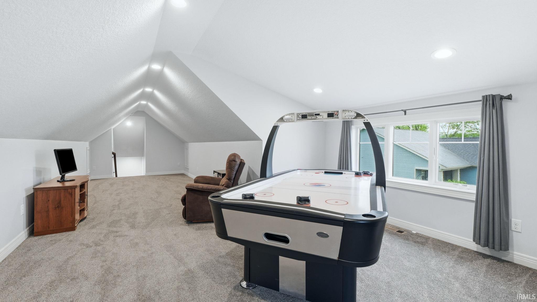 Expansive bonus room featuring vaulted ceilings with recessed lighting, plush grey carpeting, and multiple windows